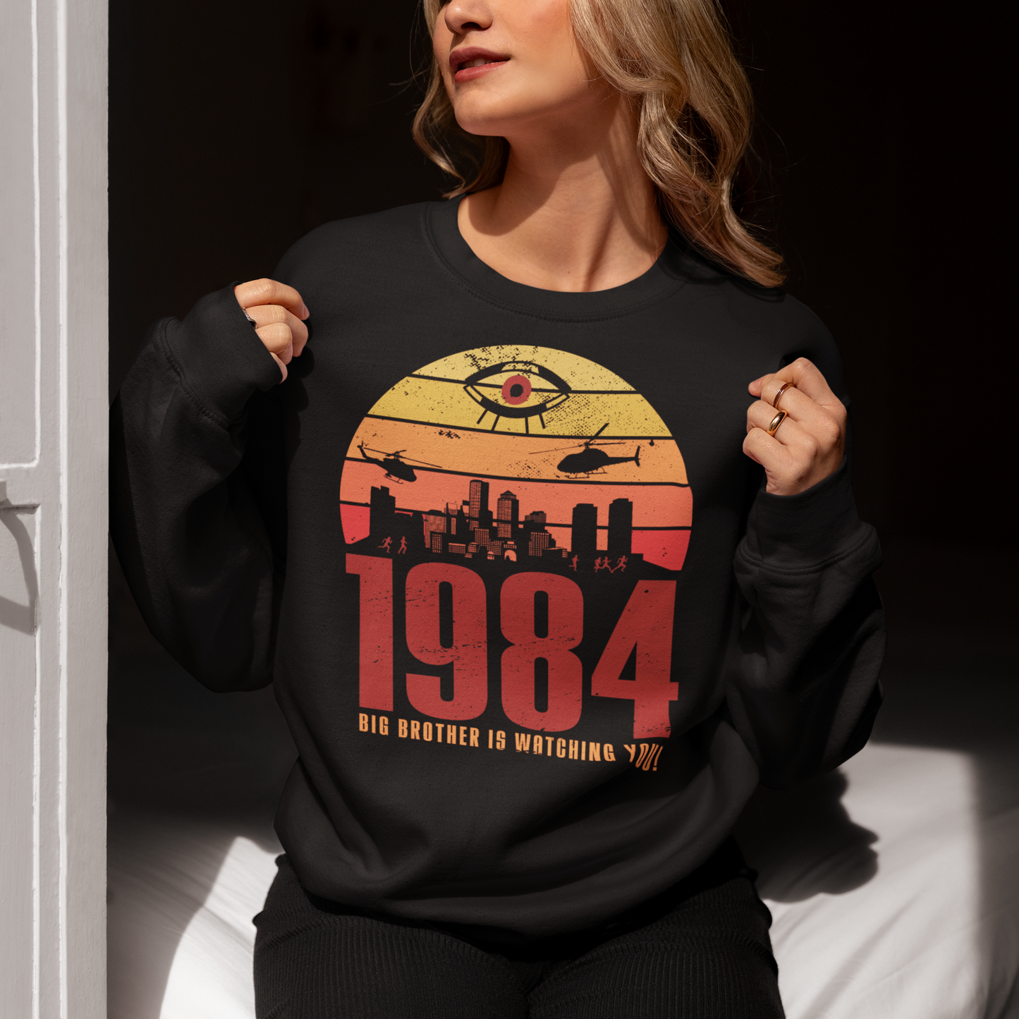Introducing our George Orwell 1984 sweatshirt with a bold "Big Brother is Watching" design! If you're a fan of Orwell's classic dystopian novel or just love thought-provoking literary references, this shirt is for you. The design features the iconic phrase "Big Brother is Watching" in small, bold letters, set against a stark sunset background. The lettering has a slightly distressed, vintage look, giving the shirt a cool, edgy vibe.
