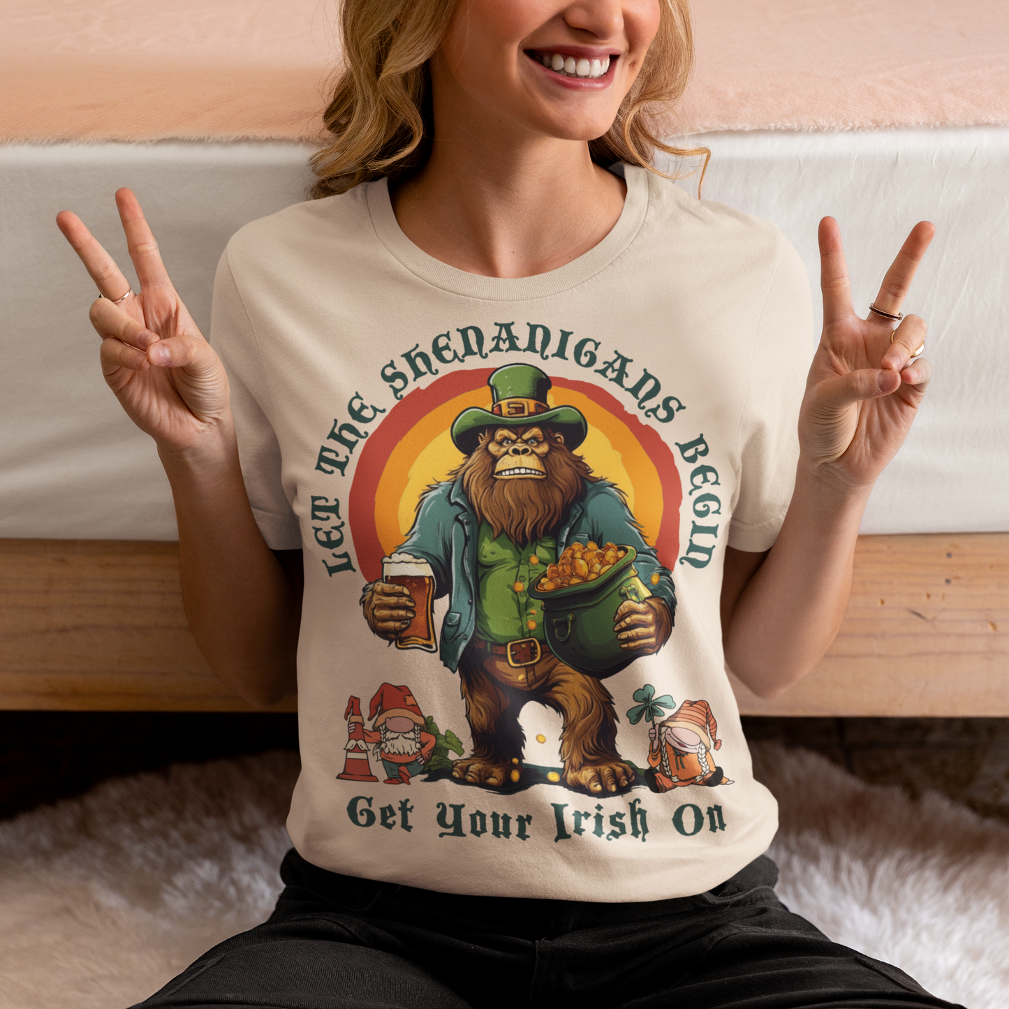 Get ready to celebrate St. Patrick's Day in style with our hilarious and festive Bigfoot-themed t-shirt! This shirt features everyone's favorite cryptid, Bigfoot, dressed in full leprechaun attire, complete with a green hat and shamrock-adorned vest. Bigfoot is depicted holding a frothy beer in one hand and a gleaming pot of gold in the other, ready to join in the festivities. Above this whimsical scene, bold text declares, "LET THE SHENANIGANS BEGIN."