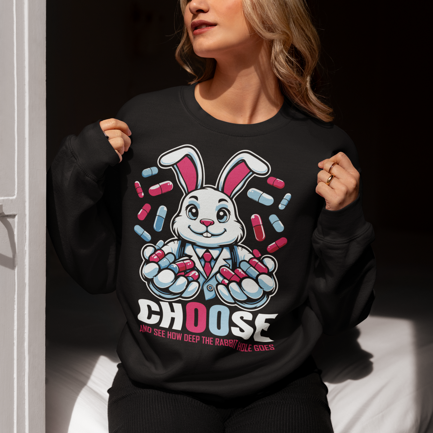 Embrace the enigmatic allure of the unknown with our captivating sweatshirt design featuring a white rabbit holding contrasting blue and red pills. This imagery beckons you to ponder the choices that define your journey. Beneath the striking illustration, bold text reads: "CHOOSE AND SEE HOW DEEP THE RABBIT HOLE GOES," inviting wearers to contemplate the consequences of their decisions and embark on a quest for truth, discovery, and self-awareness.