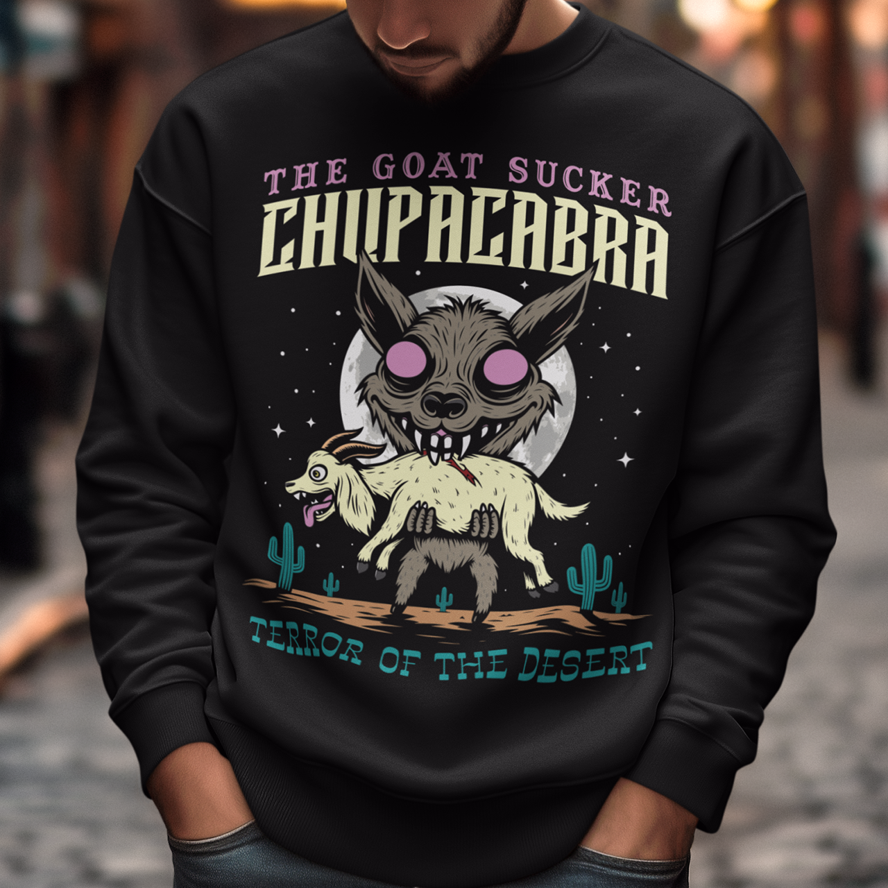 Black sweatshirt of a chupacabra sucking on a goat in the desert with text above THE GOAT SUCKER CHUPACABRA ang text below TERROR OF THE DESERT.