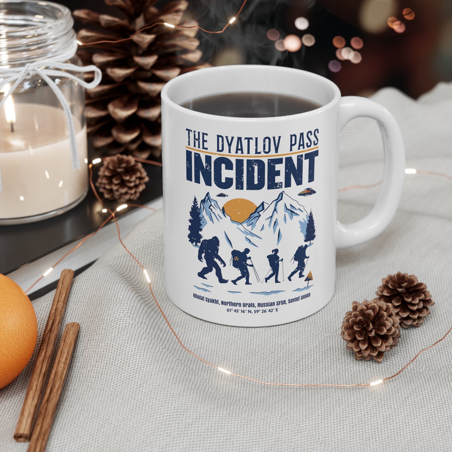 White mug of 3 hikers including Bigfoot in snowy mountains with UFOs and text THE DYATLOV PASS INCIDENT.
