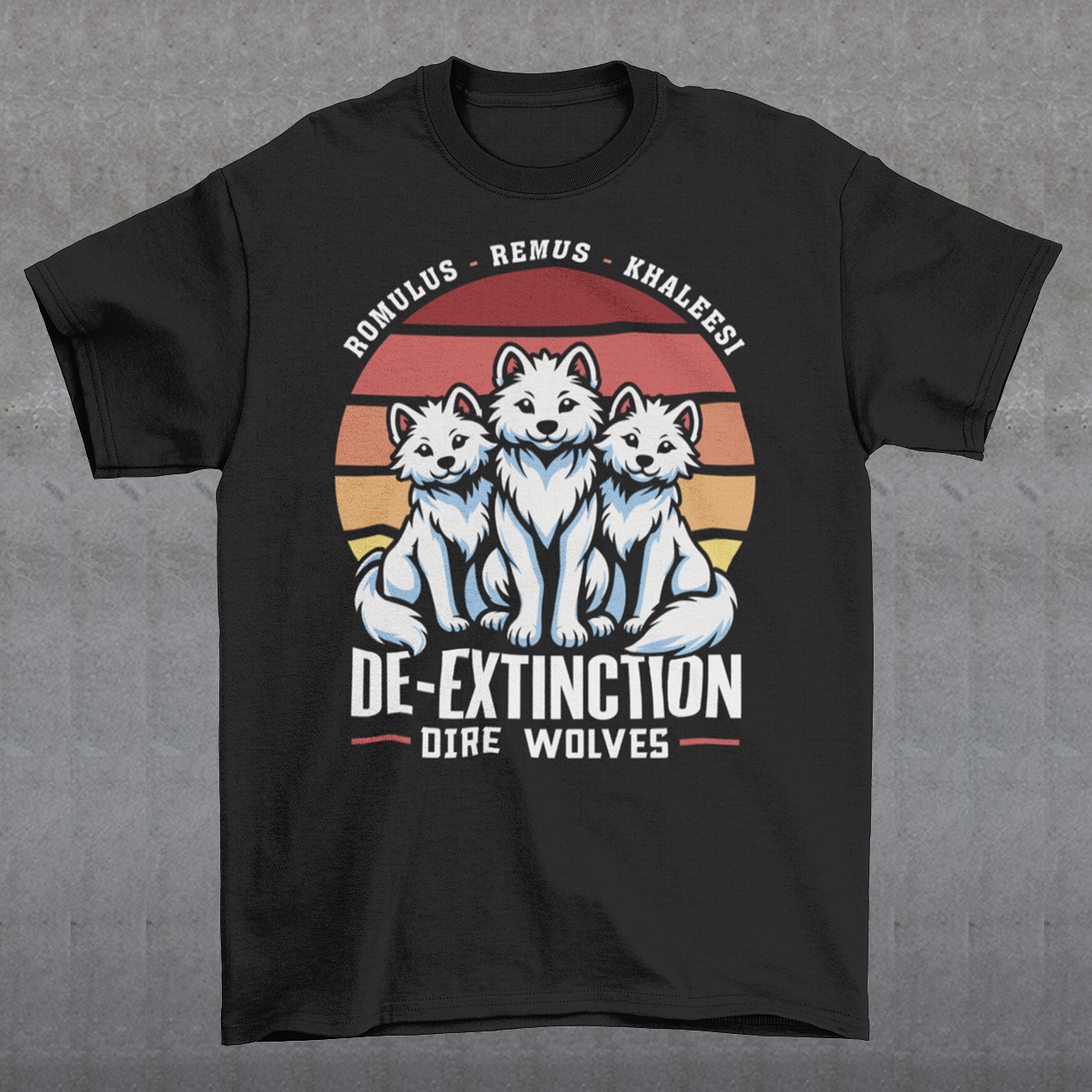 A graphic t-shirt design featuring three majestic Dire Wolves sitting side by side, facing forward with alert expressions. Behind them is a large, stylized retro sun composed of horizontal stripes in warm tones of orange, red, and yellow, evoking a vintage 80s aesthetic. Beneath the wolves, bold text reads “DE-EXTINCTION,” suggesting the return of these prehistoric predators. The design blends prehistoric imagery with nostalgic retro-futurism.
