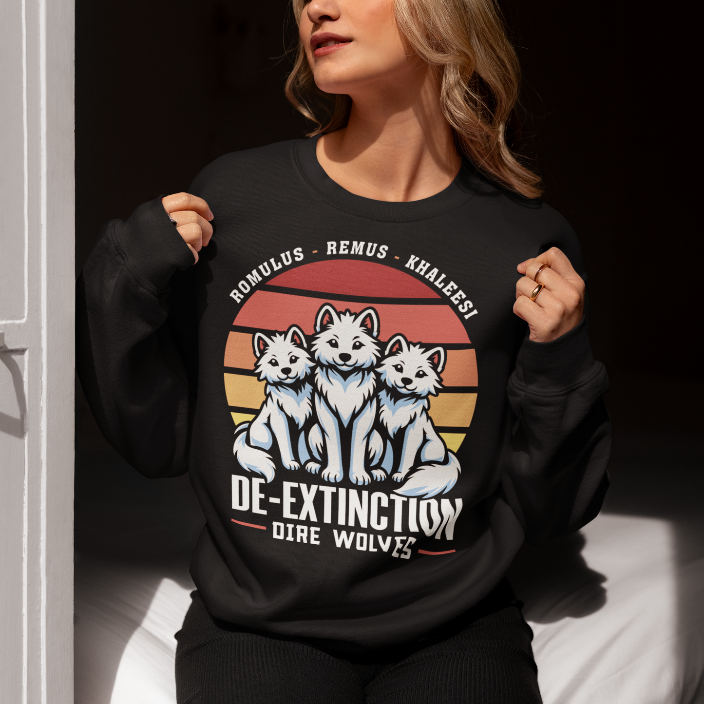 Black sweatshirt of three Dire Wolves sitting in front of a retro sun with text below DE-EXTINCTION.