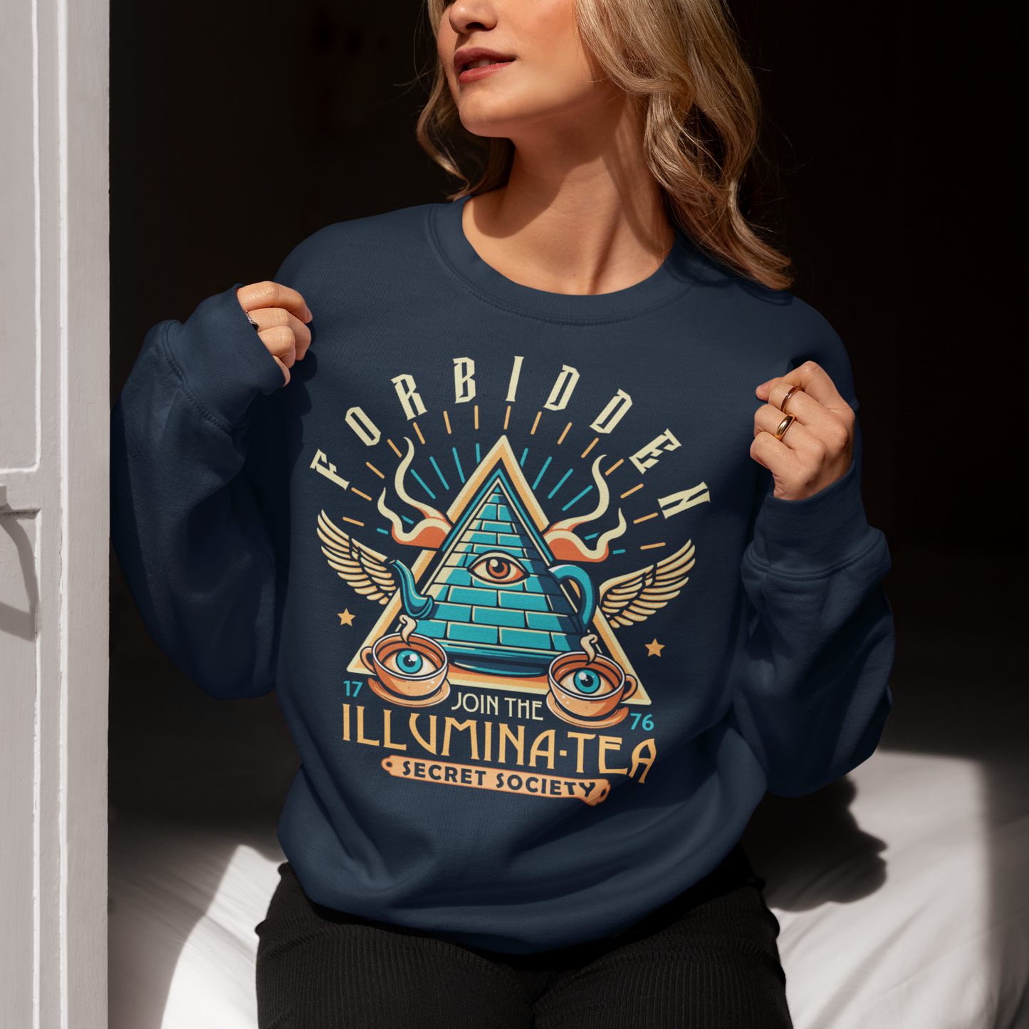 Step into the mysterious world of the Illuminati with this enigmatic sweatshirt featuring a captivating design of a tea pot and cups, each adorned with iconic Illuminati symbols. Delve into the depths of secrecy as you sip your tea, knowing that you possess the knowledge of the ages. With its clever wordplay, the text "ILLUMINA-TEA" adds a playful twist, inviting intrigue and curiosity from those around you.
