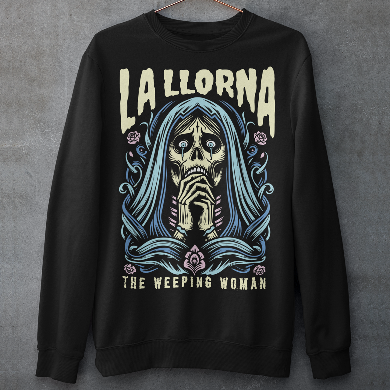 This striking La Llorona sweatshirt features a haunting depiction of the legendary Weeping Woman, her ghostly figure shrouded in mist, with flowing hair and a sorrowful expression as she searches for her lost children. The design captures the eerie, chilling essence of the famous Latin American folktale, blending dark, gothic tones with an ethereal glow. Above the image, bold lettering reads "LA LLORONA", while below, the translation "THE WEEPING WOMAN" adds to the eerie mystique.