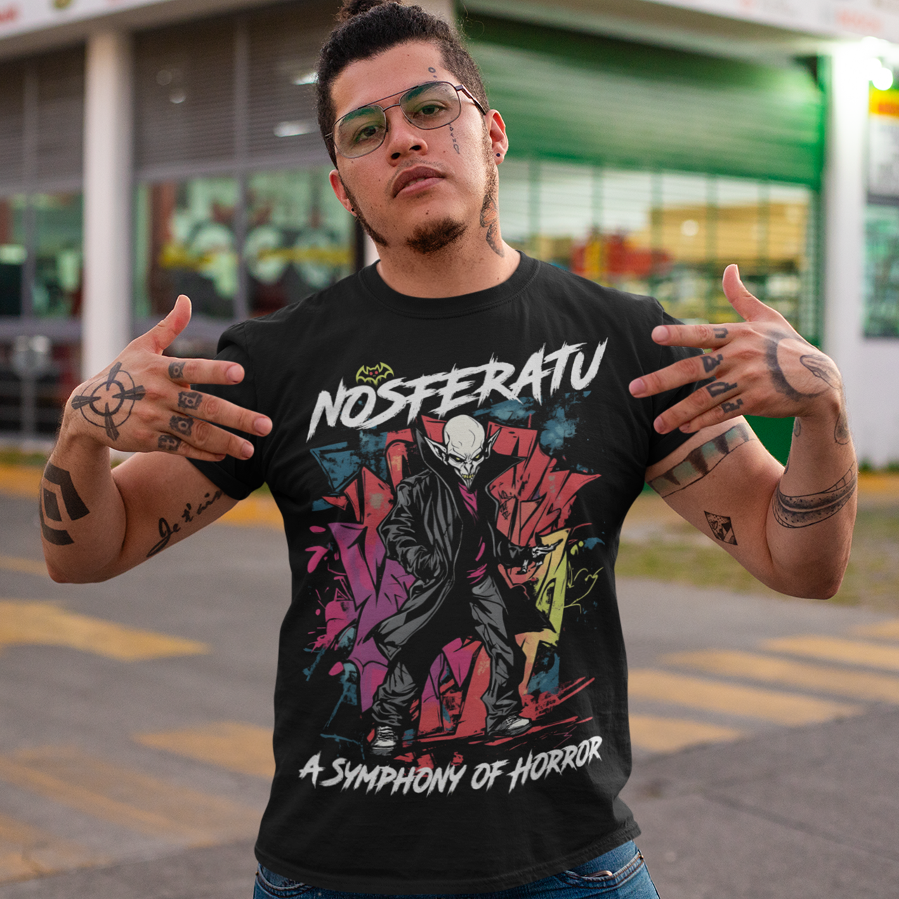 This bold graffiti-style Nosferatu T-Shirt fuses street art with classic horror. The design features a menacing, stylized depiction of Count Orlok with exaggerated, sharp features rendered in vibrant sprays and drips of color, mimicking the gritty texture of urban graffiti. Above the design, the text "NOSFERATU" stands out in bold, dripping block letters, while below, the phrase "A SYMPHONY OF HORROR" is written in an ominous, hand-scrawled font.