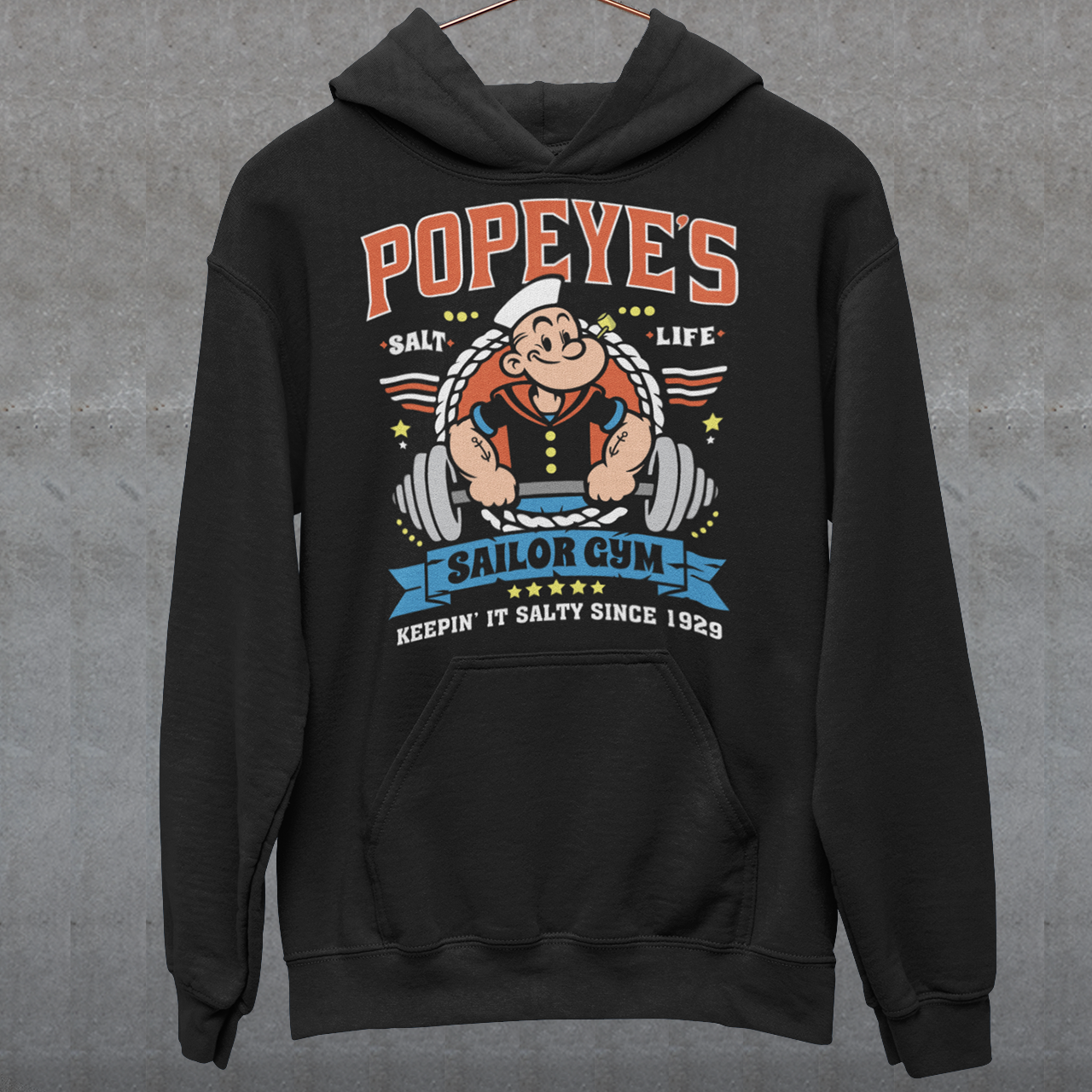 Hit the gym like a legend with the Popeye’s Sailor Gym Hoodie! Inspired by everyone’s favorite spinach-powered sailor, this shirt is perfect for lifting, lounging, or showing off your old-school strength. Featuring a vintage-style graphic of Popeye pumping iron with the slogan "Keepin' It Salty Since 1929", this tee brings serious muscle and serious nostalgia.