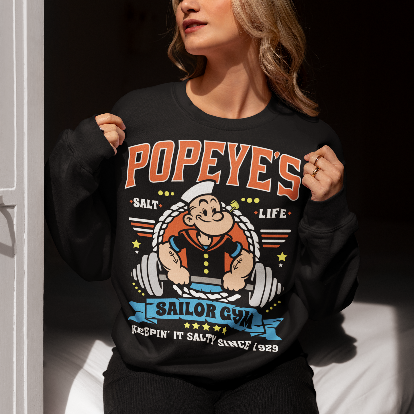 Hit the gym like a legend with the Popeye’s Sailor Gym Sweatshirt! Inspired by everyone’s favorite spinach-powered sailor, this shirt is perfect for lifting, lounging, or showing off your old-school strength. Featuring a vintage-style graphic of Popeye pumping iron with the slogan "Keepin' It Salty Since 1929", this tee brings serious muscle and serious nostalgia.