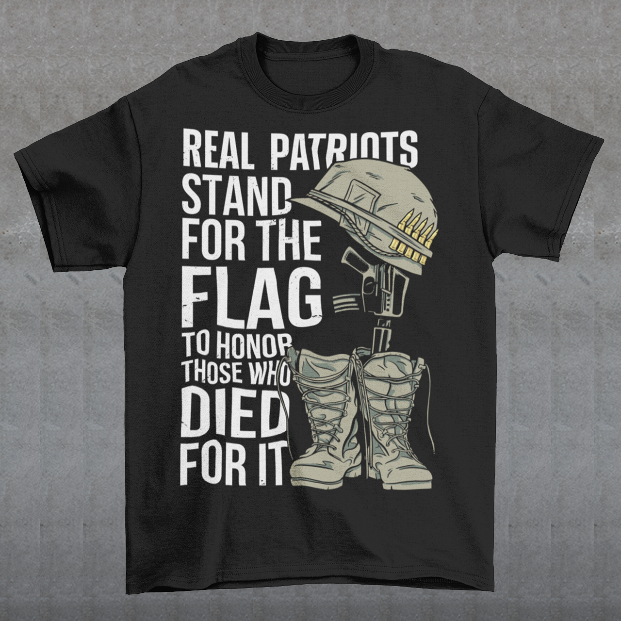 -shirt design featuring a graphic of a military helmet resting on a rifle, which is standing upright in a pair of combat boots—a battlefield cross symbolizing fallen soldiers. Above and below the image is bold text that reads: "REAL PATRIOTS STAND FOR THE FLAG TO HONOR THOSE WHO DIED FOR IT." The design uses patriotic imagery to emphasize respect and remembrance for military service members who have sacrificed their lives.