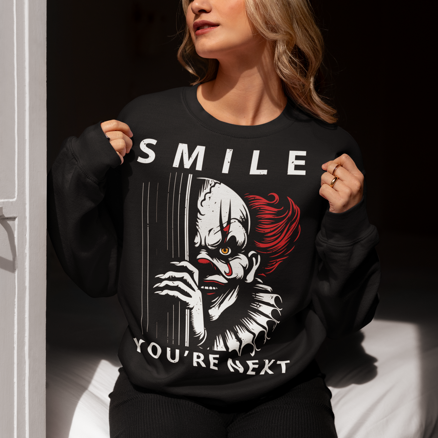 Introducing our chillingly captivating sweatshirt design, "SMILE YOU'RE NEXT." This bone-chilling masterpiece features a sinister, grinning killer clown, designed to send shivers down your spine. The intricate details of the clown's malevolent expression are both mesmerizing and haunting, drawing you into the depths of its dark persona.