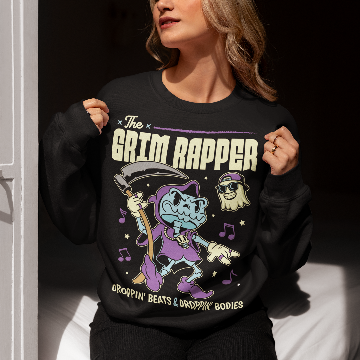 Introducing our electrifying "The Grim Rapper" Sweatshirt – a fusion of humor, music, and the afterlife that will make heads turn and beats drop! This exclusive design features a lively cartoon rendition of the Grim Reaper, decked out in rap gear confidently dropping rhymes. Surrounding the Grim Rapper are playful musical notes that dance in harmony with the rhythm. Above the charismatic cartoon character, bold text proudly declares, "THE GRIM RAPPER."