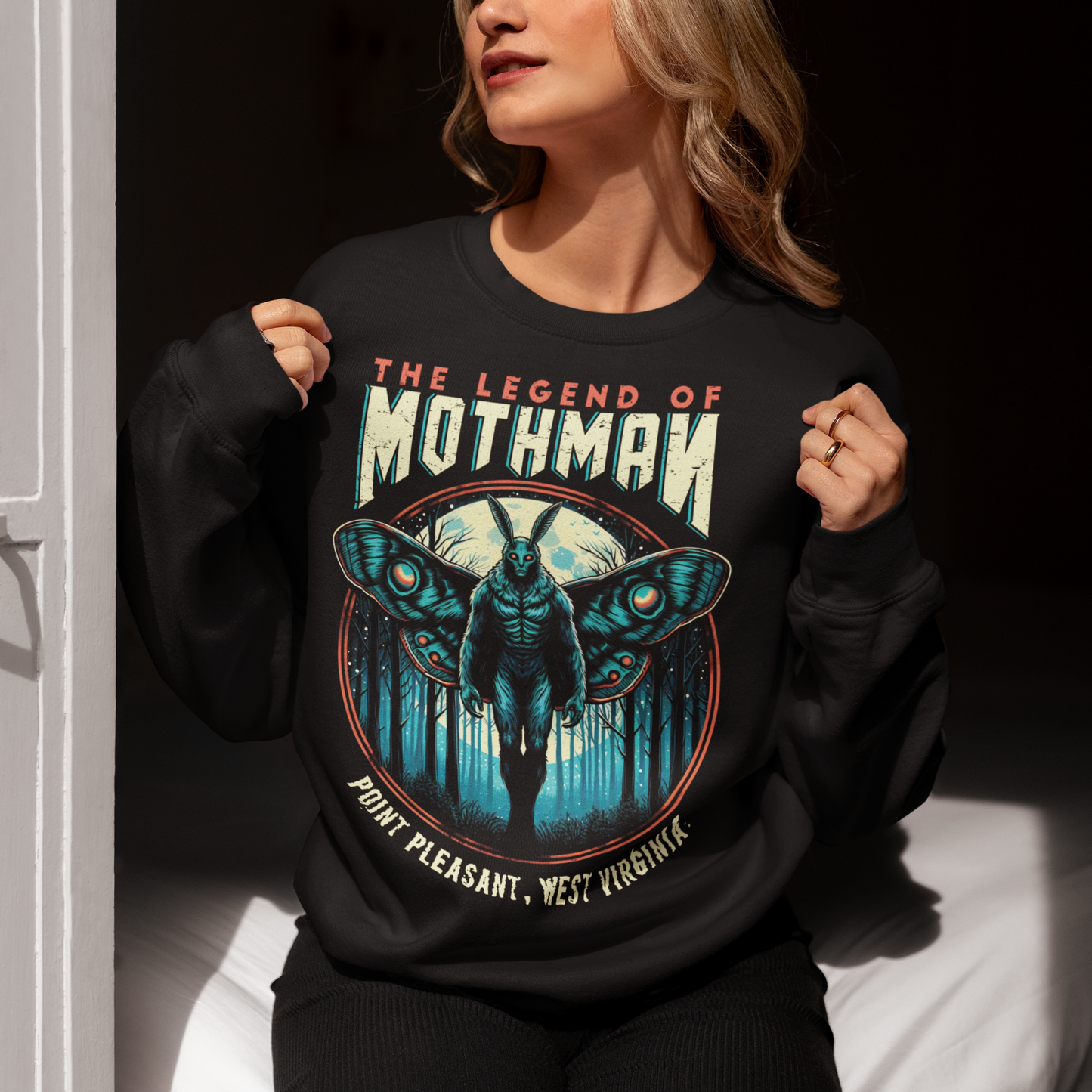 This captivating sweatshirt features a striking illustration of Mothman, the legendary cryptid, standing mysteriously in a dense, shadowy forest. The eerie scene captures the essence of folklore, with Mothman's glowing red eyes piercing through the darkness, creating an atmosphere of both intrigue and suspense. Above the enigmatic figure, bold text reads "THE LEGEND OF MOTHMAN," adding to the mystique and allure of this mythical creature.