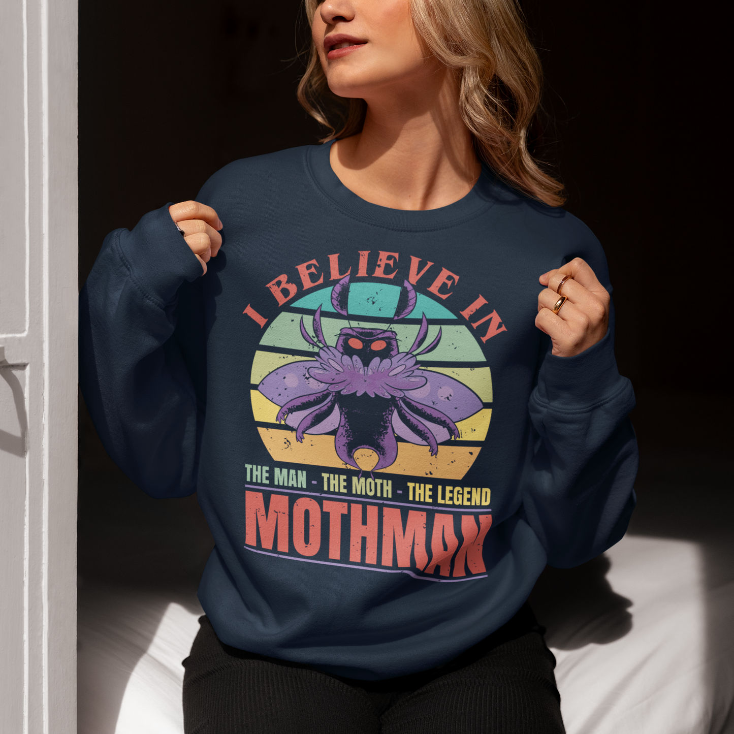 Introducing our legendary Mothman sweatshirt, a must-have for believers and enthusiasts alike! Embrace the enigmatic allure of the Mothman phenomenon with this captivating design featuring the iconic cryptid against a retro sun background.