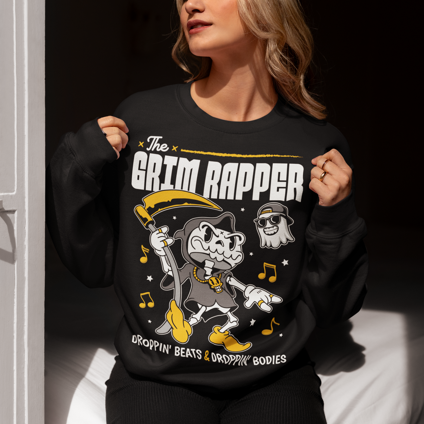Introducing our electrifying "The Grim Rapper" Sweatshirt – a fusion of humor, music, and the afterlife that will make heads turn and beats drop! This exclusive design features a lively cartoon rendition of the Grim Reaper, decked out in rap gear confidently dropping rhymes. Surrounding the Grim Rapper are playful musical notes that dance in harmony with the rhythm. Above the charismatic cartoon character, bold text proudly declares, "THE GRIM RAPPER."