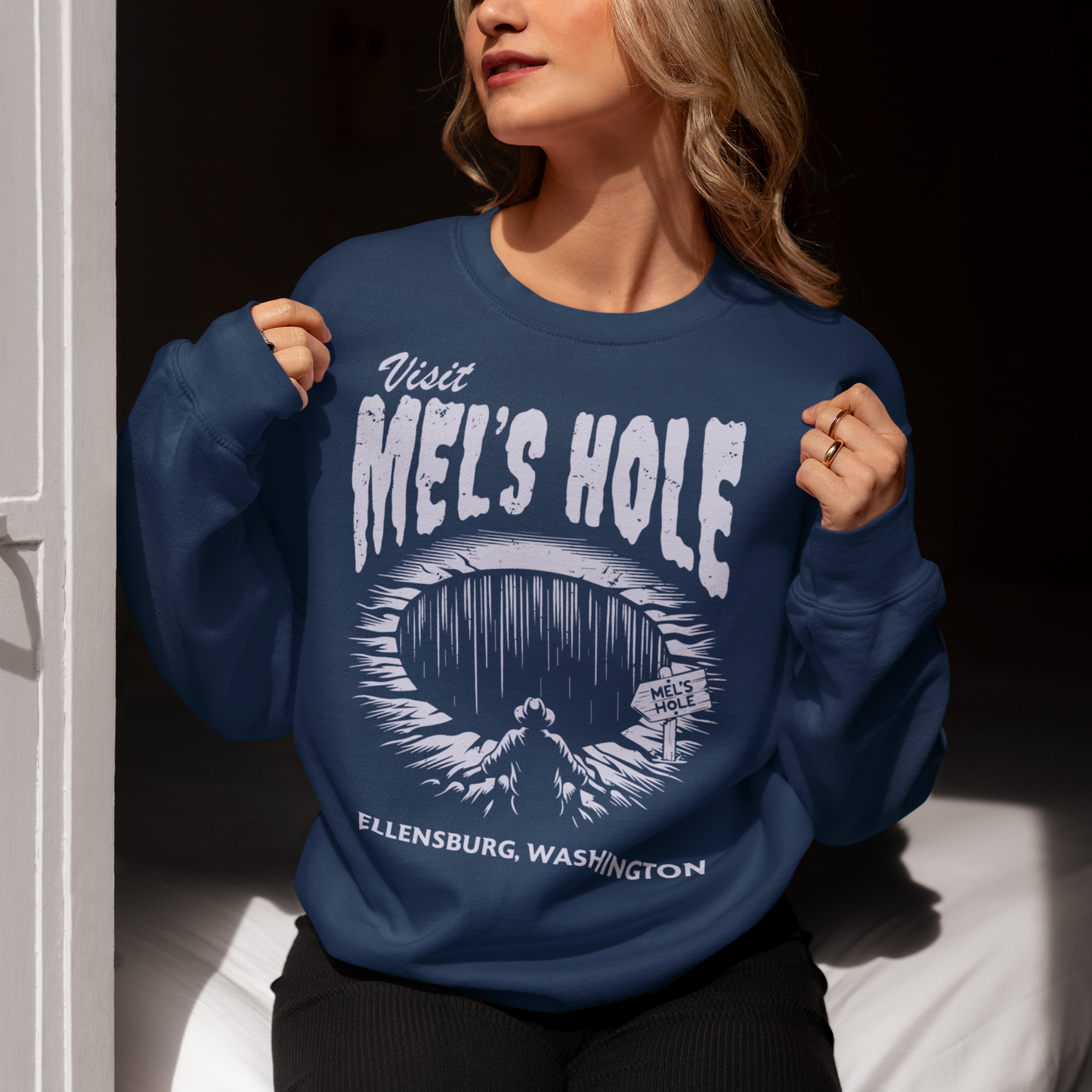 Step into the strange with this quirky and mysterious shirt! Featuring a bold illustration of a curious man peering into a dark, bottomless abyss, this shirt pays homage to the legendary paranormal tale of Mel's Hole — a supposed infinite pit in the wilds of Washington State. The vintage-style artwork is topped with the eerie invitation: "VISIT MEL'S HOLE" in retro tourism font, blending humor, folklore, and a dash of the unexplained.