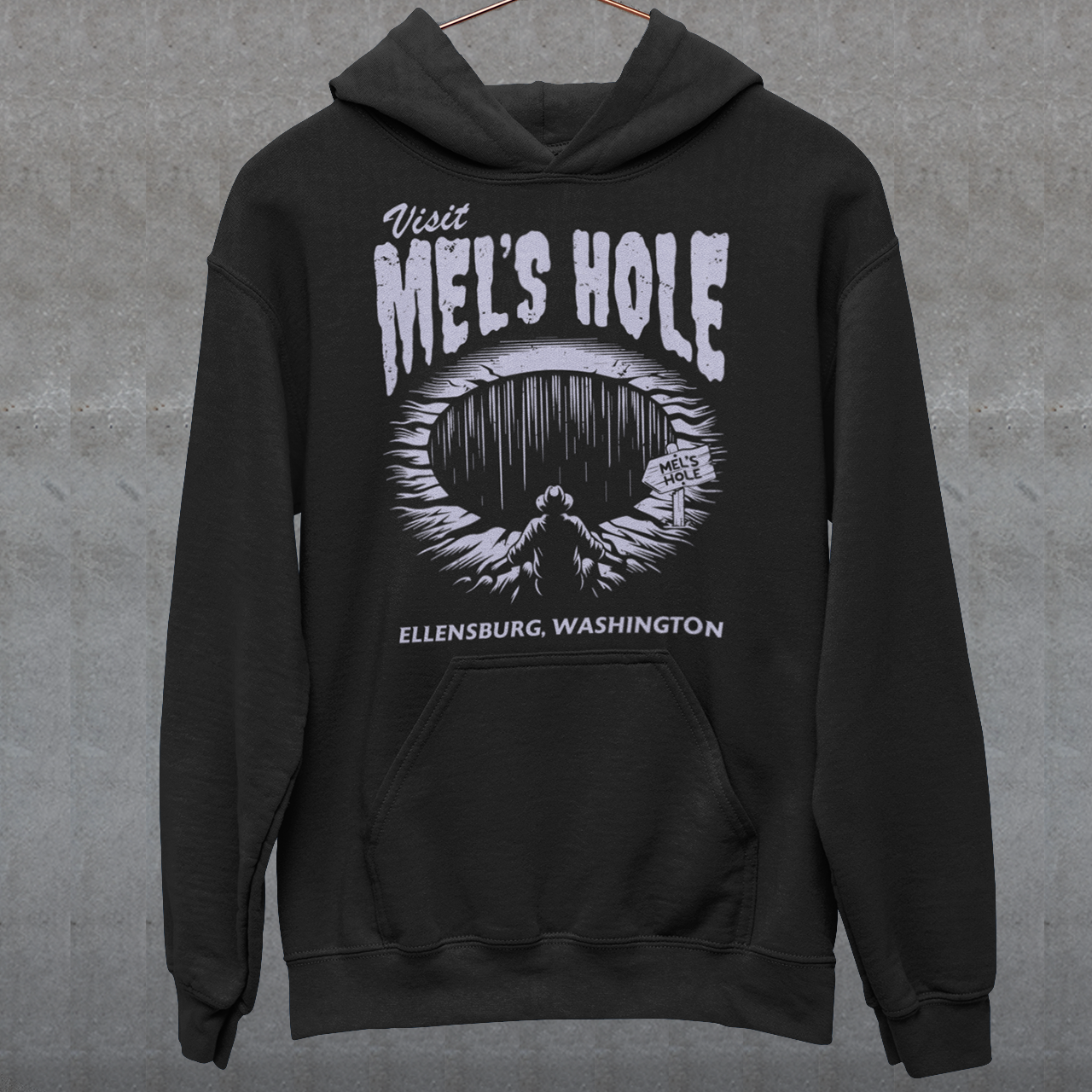 Step into the strange with this quirky and mysterious hoodie! Featuring a bold illustration of a curious man peering into a dark, bottomless abyss, this hoodie pays homage to the legendary paranormal tale of Mel's Hole — a supposed infinite pit in the wilds of Washington State. The vintage-style artwork is topped with the eerie invitation: "VISIT MEL'S HOLE" in retro tourism font, blending humor, folklore, and a dash of the unexplained.