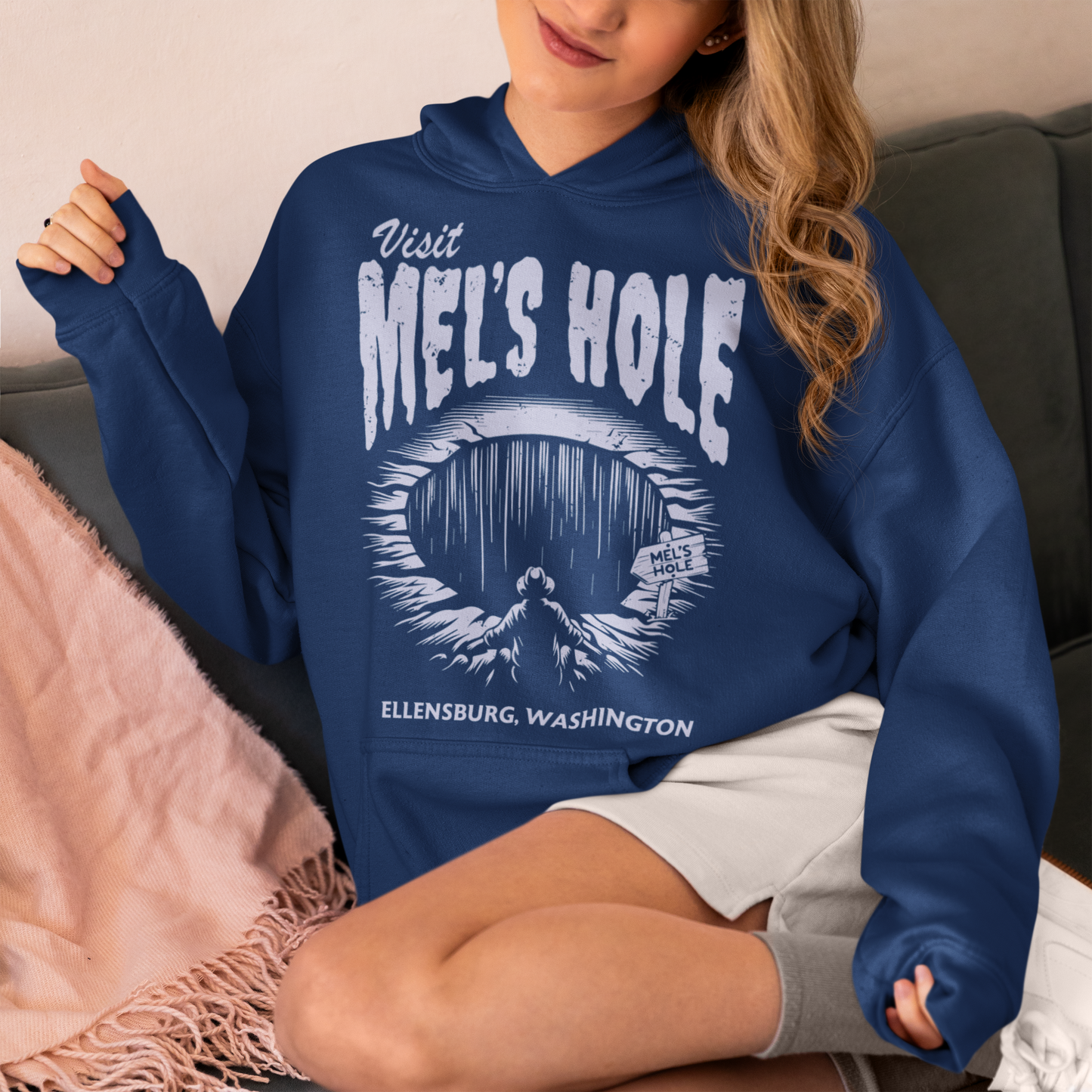 Step into the strange with this quirky and mysterious hoodie! Featuring a bold illustration of a curious man peering into a dark, bottomless abyss, this hoodie pays homage to the legendary paranormal tale of Mel's Hole — a supposed infinite pit in the wilds of Washington State. The vintage-style artwork is topped with the eerie invitation: "VISIT MEL'S HOLE" in retro tourism font, blending humor, folklore, and a dash of the unexplained.