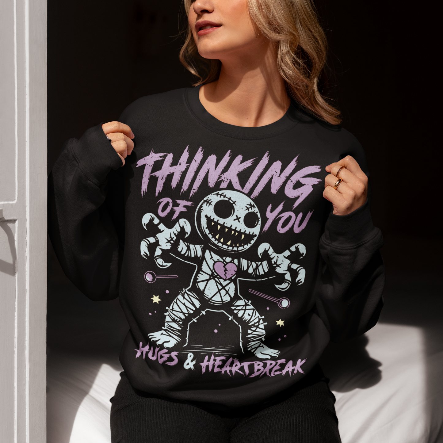 Dark humor meets twisted sweetness with this bold sweatshirt. Featuring a stitched-up voodoo doll at the center, the design captures that perfect mix of love and pain. Above the doll, the phrase “THINKING OF YOU” adds a playful sting, while below, “HUGS & HEARTBREAK” ties it all together with equal parts irony and affection. Perfect for anyone who loves edgy, alternative fashion—or just wants to send a cheeky message without saying a word.