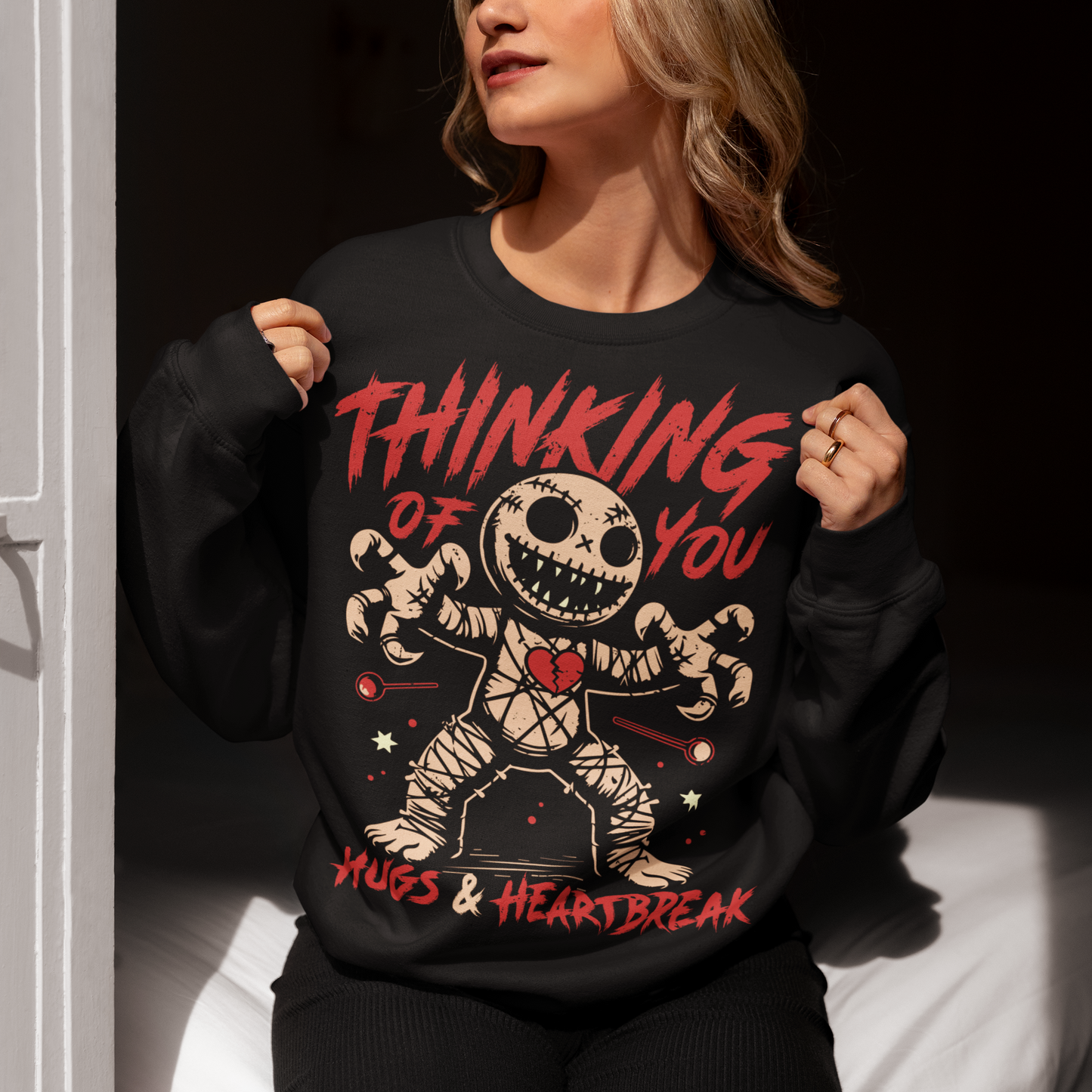 Dark humor meets twisted sweetness with this bold sweatshirt. Featuring a stitched-up voodoo doll at the center, the design captures that perfect mix of love and pain. Above the doll, the phrase “THINKING OF YOU” adds a playful sting, while below, “HUGS & HEARTBREAK” ties it all together with equal parts irony and affection. Perfect for anyone who loves edgy, alternative fashion—or just wants to send a cheeky message without saying a word.