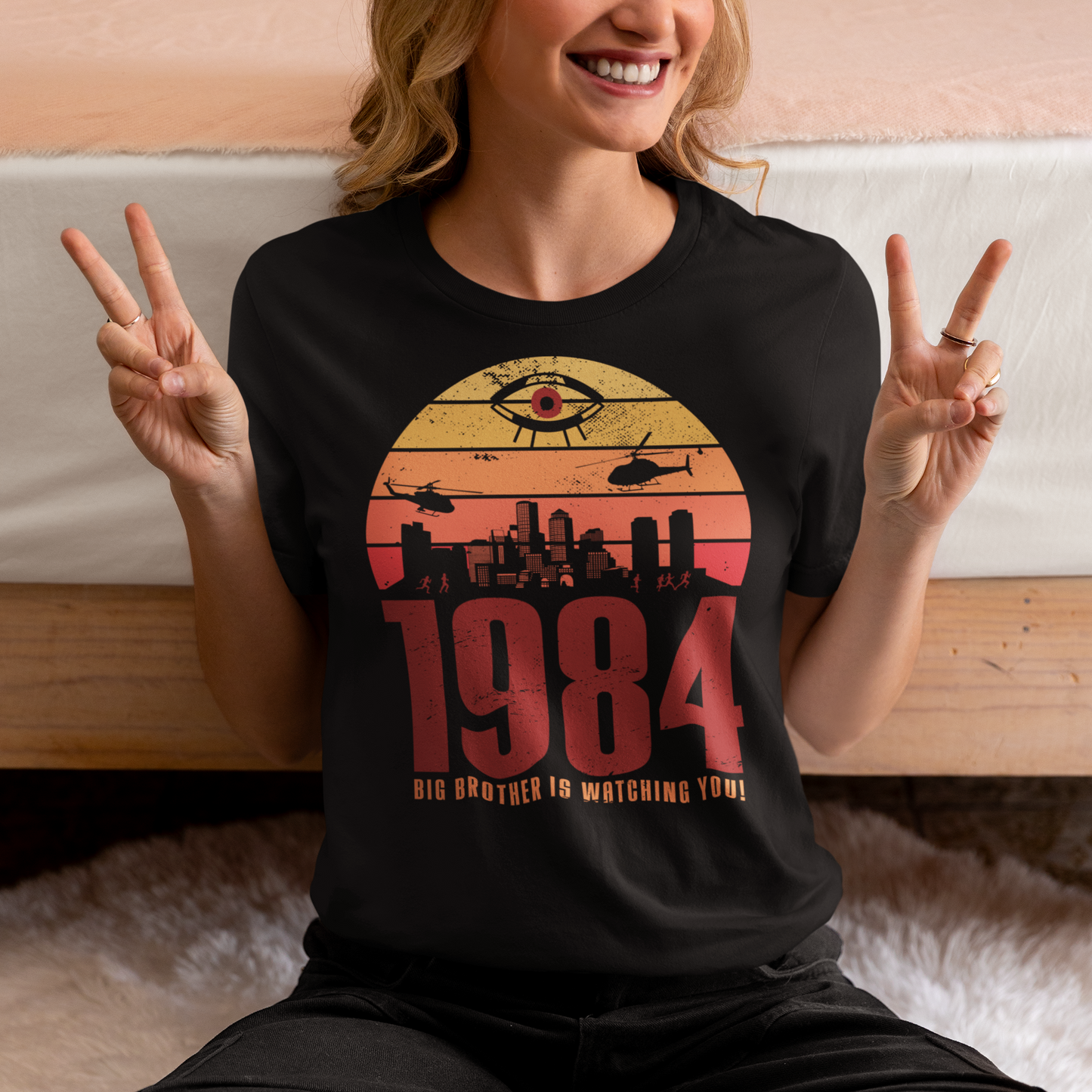 A black t-shirt with a design of a sunset with dystopian silhouette with text underneath "1984 BIG BROTHER IS WATCHING".