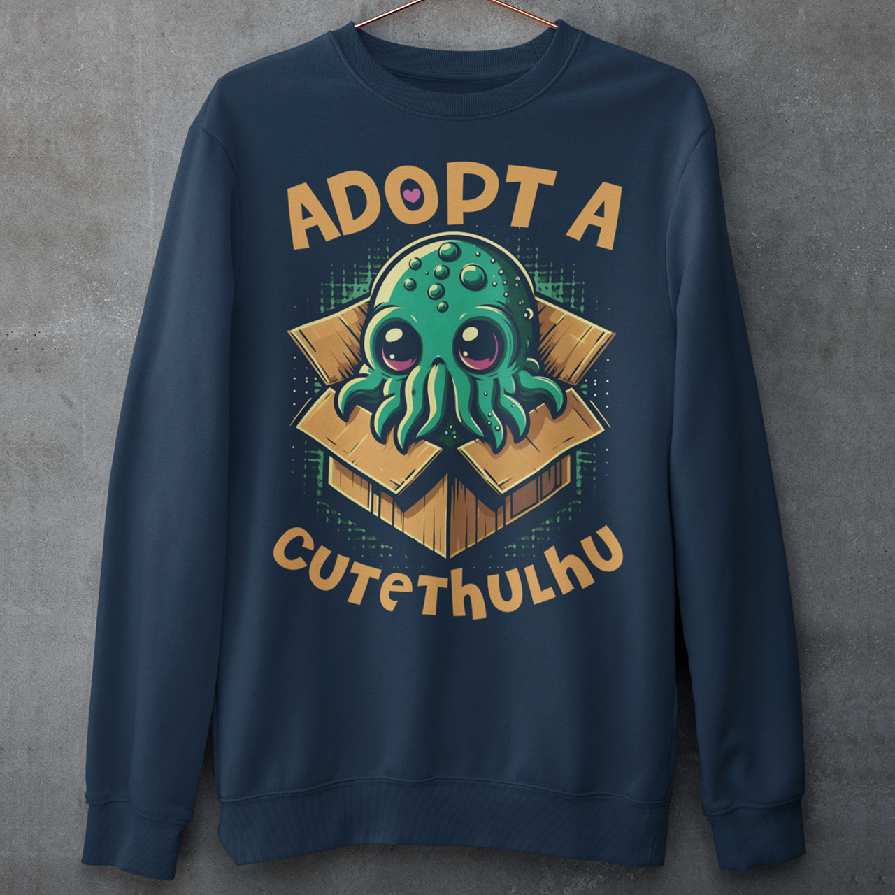 Navy sweatshirt of a cute Cthulhu in a cardboard box with text ADOPT A CUTETHULHU.