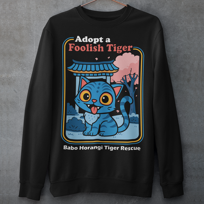 Adopt a foolish tiger t-shirt. Derpy kpop demon hunters shirt. Babo Horangi tee. This design feels like a Korean folklore creature wandered into a Saturday morning cartoon and decided to stay for snacks. A wide eyed blue “foolish tiger” sits under a temple gate with cherry blossoms drifting by, tongue out, zero survival instincts, maximum charm. The playful mix of myth inspired setting and goofy expression makes it equal parts legend and lovable disaster.on hunters shirt.