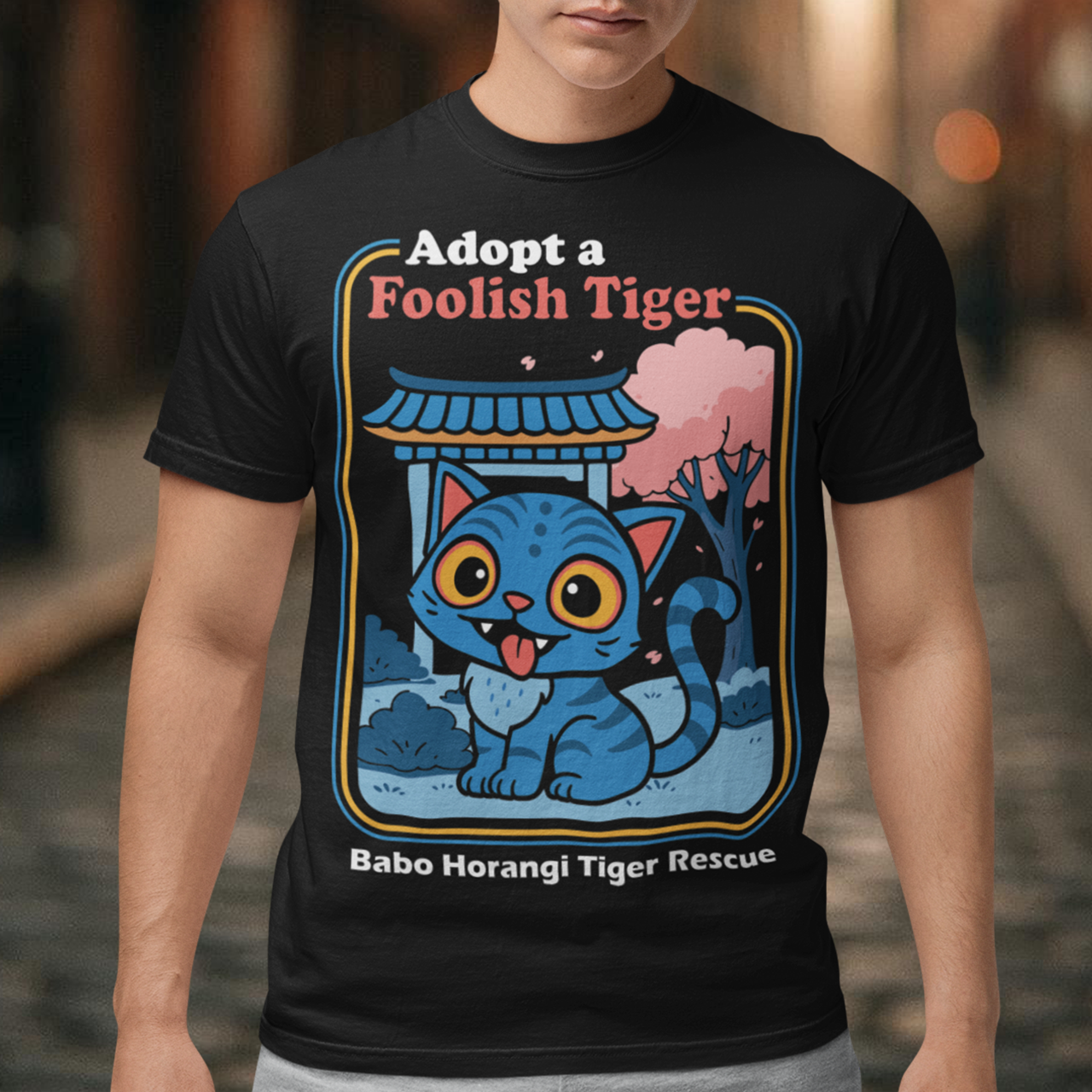 Adopt a foolish tiger t-shirt. Derpy kpop demon hunters shirt. Babo Horangi tee. This design feels like a Korean folklore creature wandered into a Saturday morning cartoon and decided to stay for snacks. A wide eyed blue “foolish tiger” sits under a temple gate with cherry blossoms drifting by, tongue out, zero survival instincts, maximum charm. The playful mix of myth inspired setting and goofy expression makes it equal parts legend and lovable disaster.on hunters shirt.