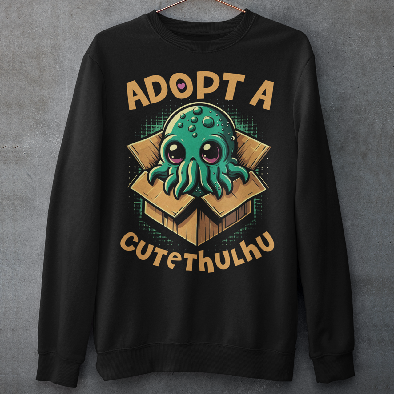 Black sweatshirt of a cute Cthulhu in a cardboard box with text ADOPT A CUTETHULHU.