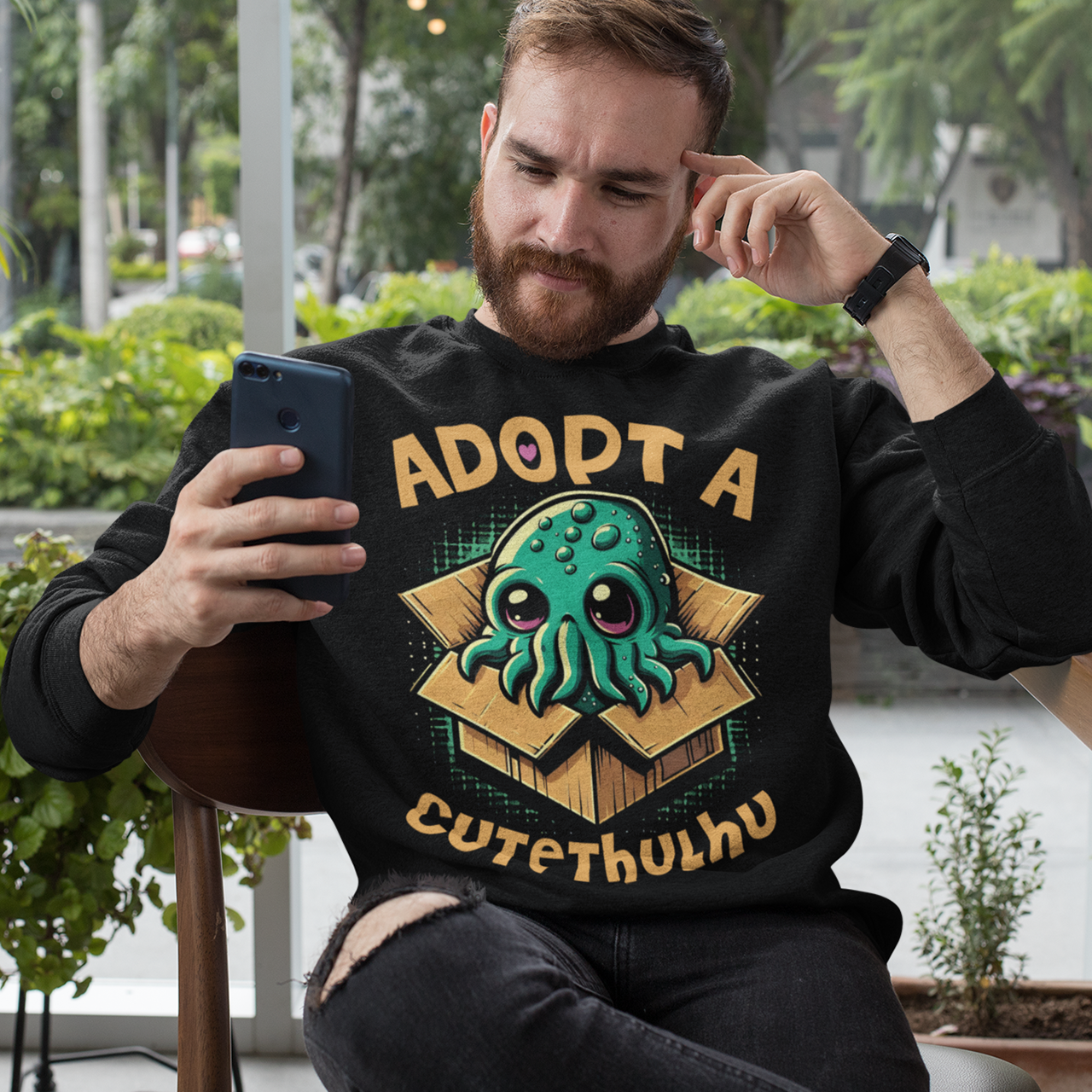 Black sweatshirt of a cute Cthulhu in a cardboard box with text ADOPT A CUTETHULHU.