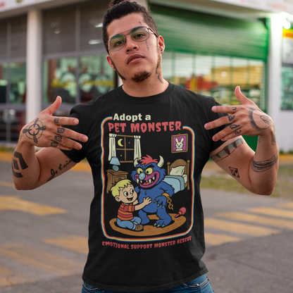 My pet monster t-shirt. Soft, spooky, and suspiciously adorable, this tee looks like it came straight from a slightly haunted Saturday morning cartoon vault. The design features a wide eyed kid befriending a fuzzy little monster with tiny horns and big attitude, all set inside a cozy bedroom scene with retro storybook vibes. The bold “Adopt a Pet Monster” headline and “Emotional Support Monster Rescue” tagline sell the joke perfectly, blending cute chaos with feel good humor.