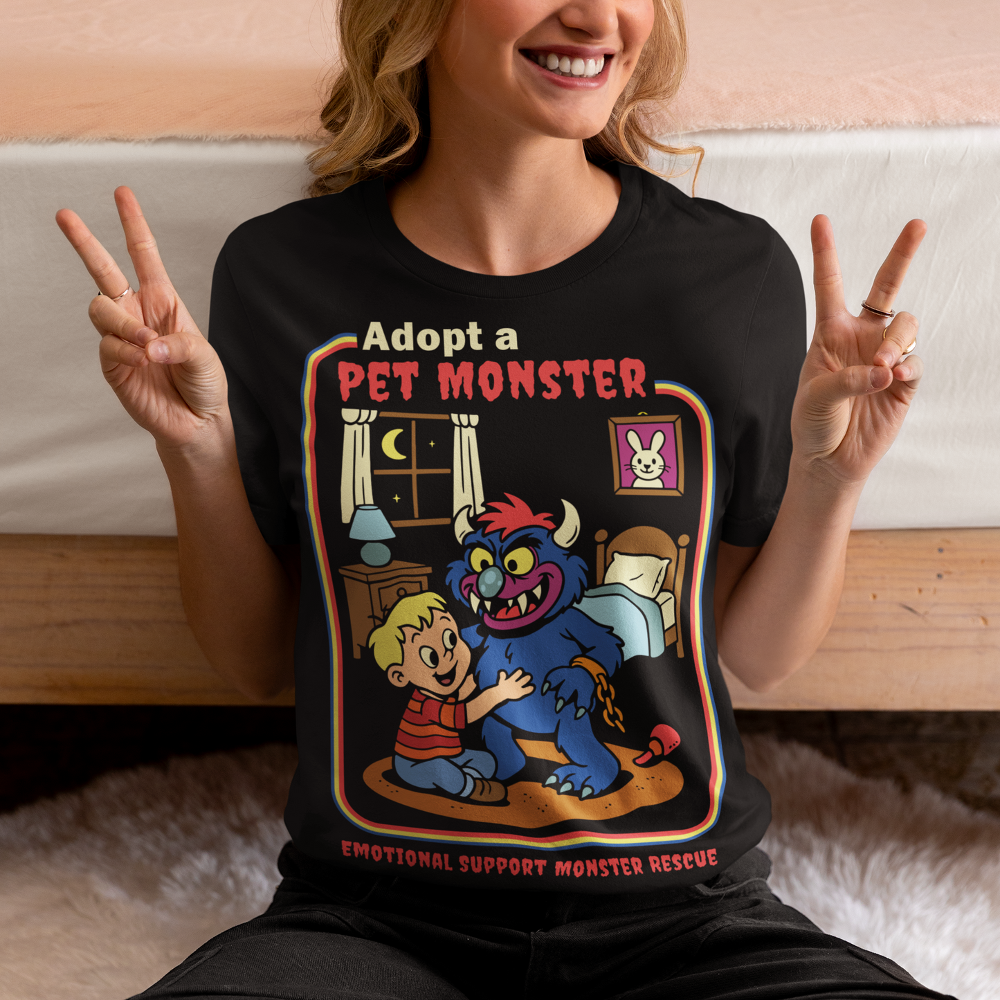 My pet monster t-shirt. Soft, spooky, and suspiciously adorable, this tee looks like it came straight from a slightly haunted Saturday morning cartoon vault. The design features a wide eyed kid befriending a fuzzy little monster with tiny horns and big attitude, all set inside a cozy bedroom scene with retro storybook vibes. The bold “Adopt a Pet Monster” headline and “Emotional Support Monster Rescue” tagline sell the joke perfectly, blending cute chaos with feel good humor.