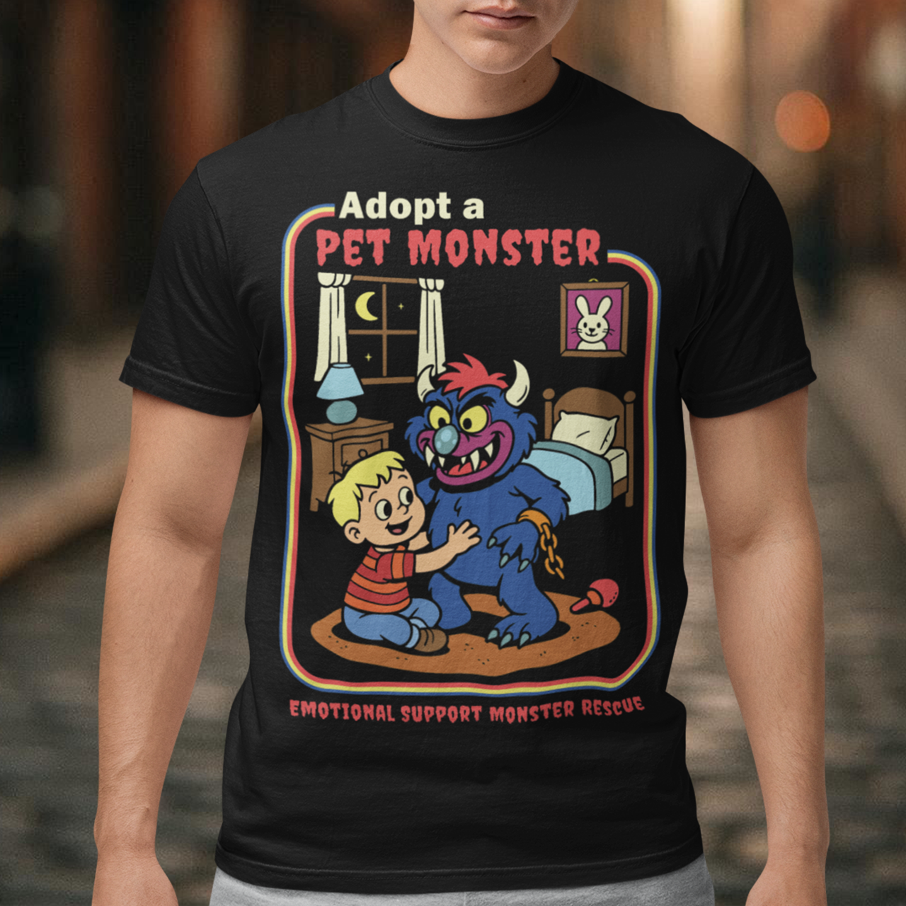 My pet monster t-shirt. Soft, spooky, and suspiciously adorable, this tee looks like it came straight from a slightly haunted Saturday morning cartoon vault. The design features a wide eyed kid befriending a fuzzy little monster with tiny horns and big attitude, all set inside a cozy bedroom scene with retro storybook vibes. The bold “Adopt a Pet Monster” headline and “Emotional Support Monster Rescue” tagline sell the joke perfectly, blending cute chaos with feel good humor.