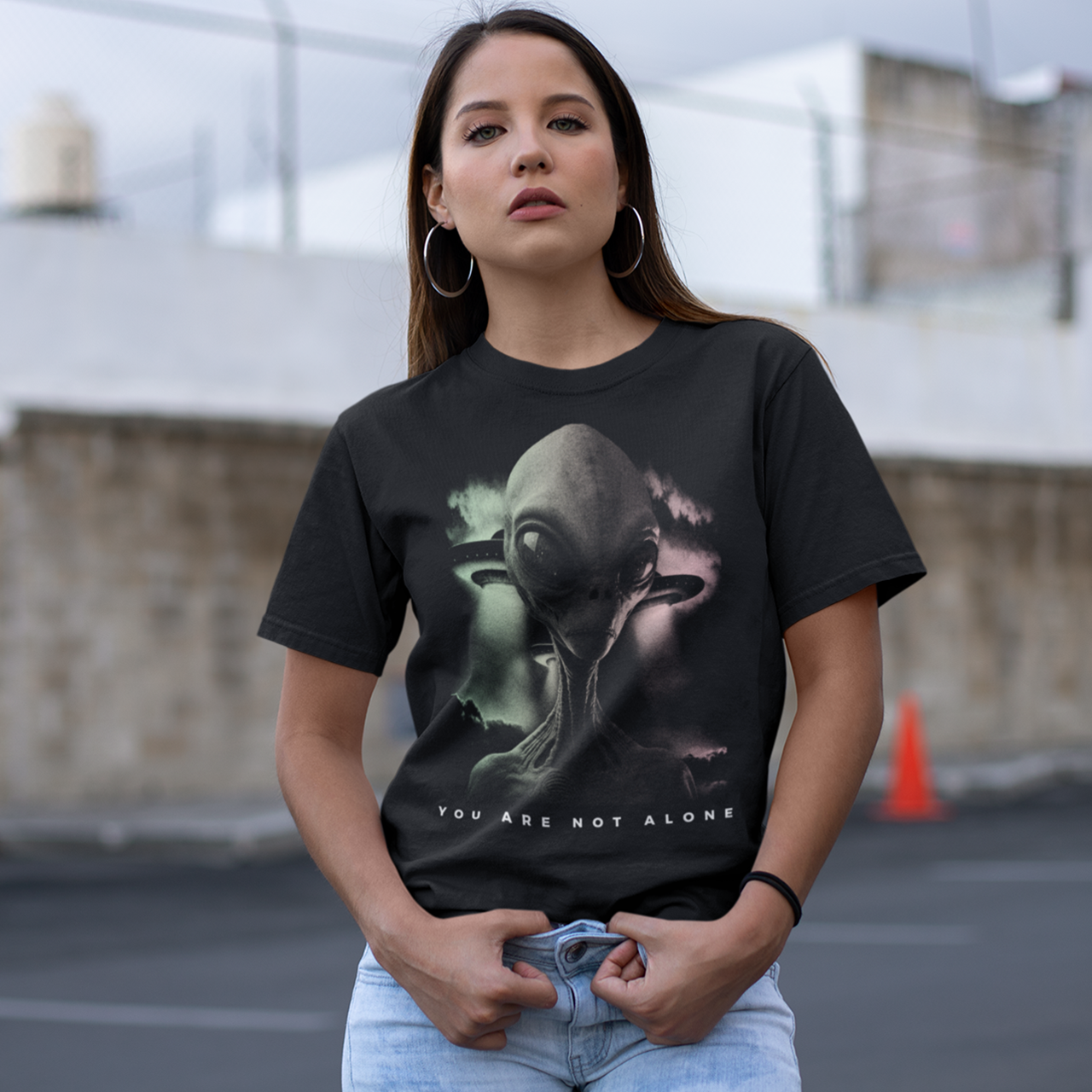 Black t-shirt of an alien with two UFOs in the background with text below "YOU ARE NOT ALONE".