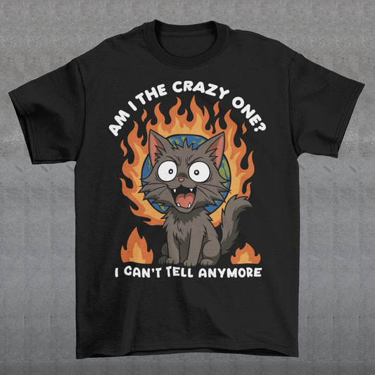 Black t-shirt featuring a cartoon gray cat with wide eyes and sharp teeth, sitting in front of a flaming globe. The design includes the text “Am I the crazy one? I can’t tell anymore” in bold white letters. The illustration has a humorous, dark tone, combining chaotic energy with a cute yet slightly unhinged cat character.
