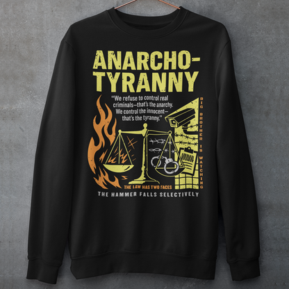 Black sweatshirt featuring a distressed yellow “ANARCHO-TYRANNY” graphic with scales of justice, flames, barbed wire, surveillance imagery, and prison-themed artwork. The design includes the phrases “THE LAW HAS TWO FACES” and “THE HAMMER FALLS SELECTIVELY,” creating a bold political statement focused on authority, government power, civil liberties, and anti-authoritarian themes.