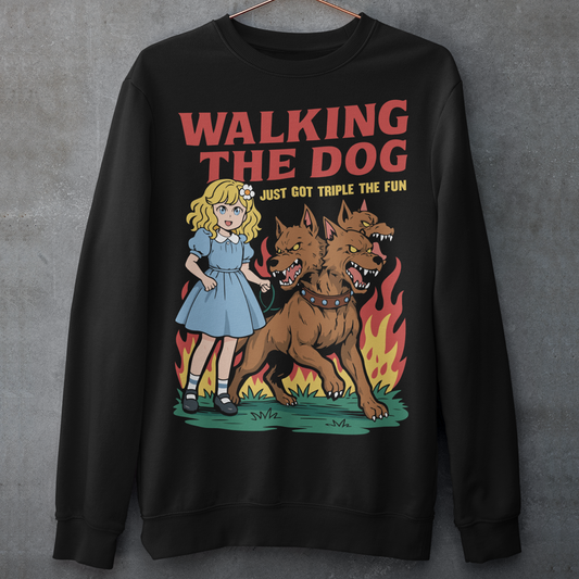 Black Sweatshirt featuring a colorful cartoon design of a young girl in a blue dress casually walking a three-headed Cerberus dog on a leash. The fierce hellhound snarls with sharp teeth while flames rise behind it, creating a striking contrast between cute and chaotic. Bold red text reads “Walking the Dog” with smaller text below saying “Just Got Triple the Fun,” adding humor to the fantasy-inspired scene.
