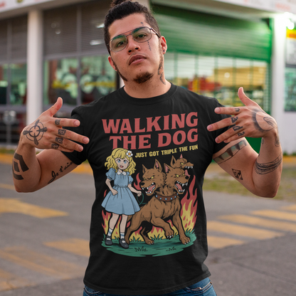 Black t-shirt featuring a colorful cartoon design of a young girl in a blue dress casually walking a three-headed Cerberus dog on a leash. The fierce hellhound snarls with sharp teeth while flames rise behind it, creating a striking contrast between cute and chaotic. Bold red text reads “Walking the Dog” with smaller text below saying “Just Got Triple the Fun,” adding humor to the fantasy-inspired scene.
