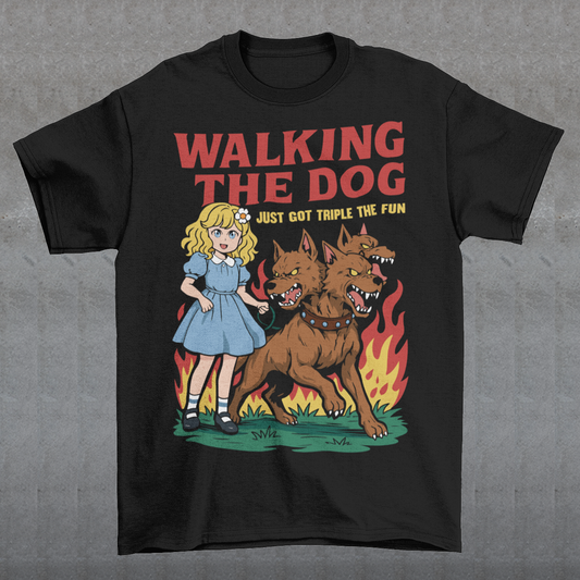 Black t-shirt featuring a colorful cartoon design of a young girl in a blue dress casually walking a three-headed Cerberus dog on a leash. The fierce hellhound snarls with sharp teeth while flames rise behind it, creating a striking contrast between cute and chaotic. Bold red text reads “Walking the Dog” with smaller text below saying “Just Got Triple the Fun,” adding humor to the fantasy-inspired scene.