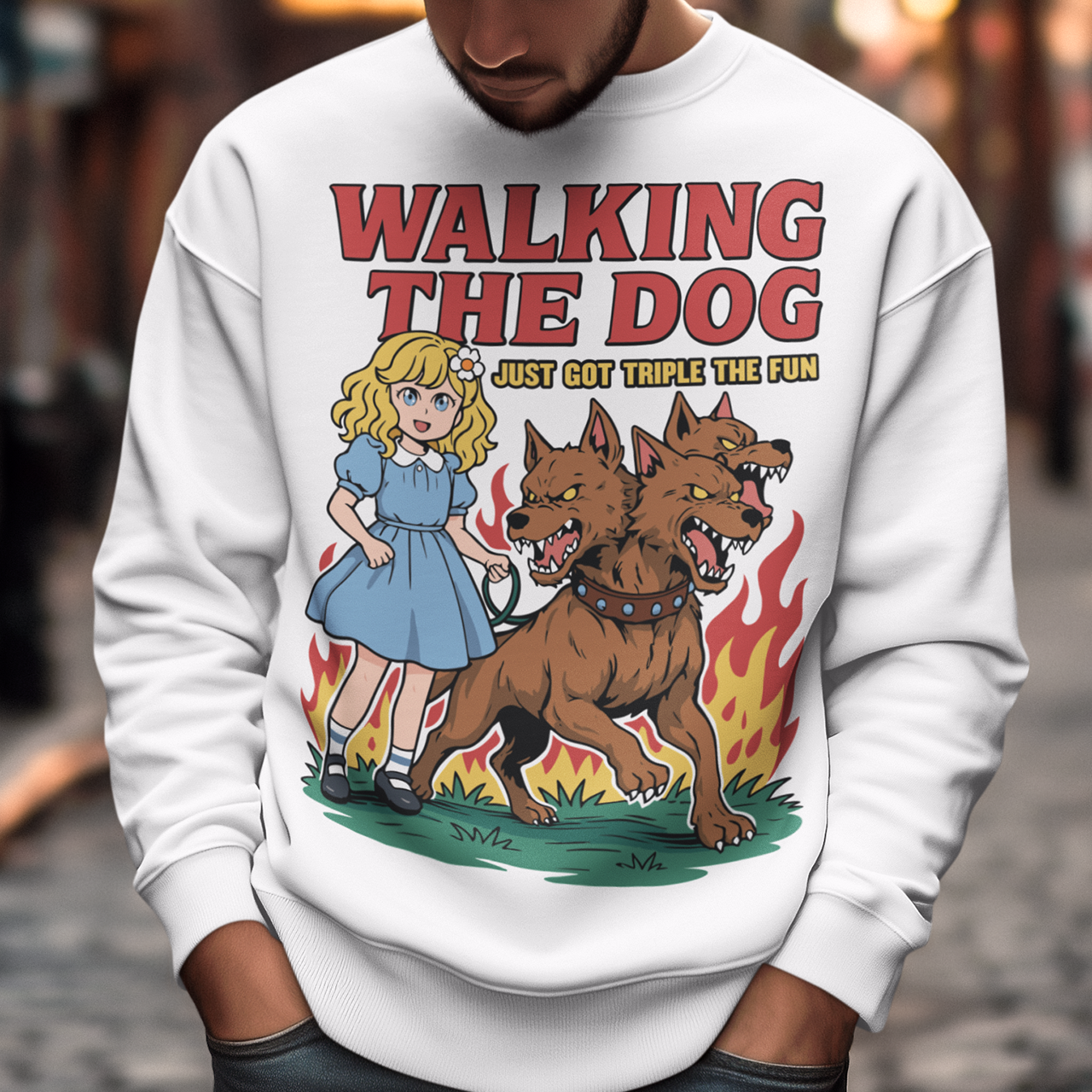 White Sweatshirt featuring a colorful cartoon design of a young girl in a blue dress casually walking a three-headed Cerberus dog on a leash. The fierce hellhound snarls with sharp teeth while flames rise behind it, creating a striking contrast between cute and chaotic. Bold red text reads “Walking the Dog” with smaller text below saying “Just Got Triple the Fun,” adding humor to the fantasy-inspired scene.