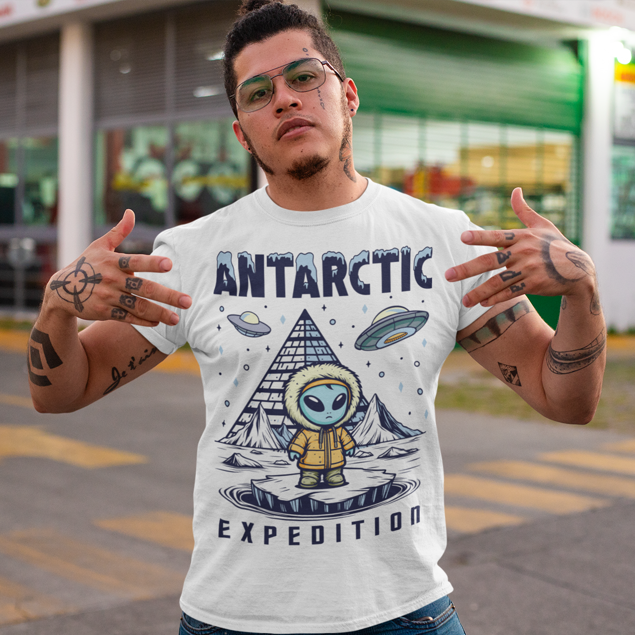 White t-shirt of an Alien wearing a jacket in Antarctica with a pyramid in the background and UFOs in the sky with text ANTARCTIC EXPEDITION.