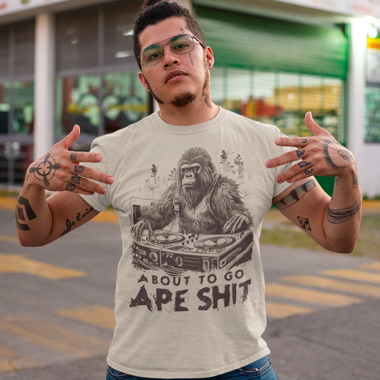 Cream t-shirt with a gorilla playing the decks in a forest with text underneath "ABOUT TO GO APE SHIT".