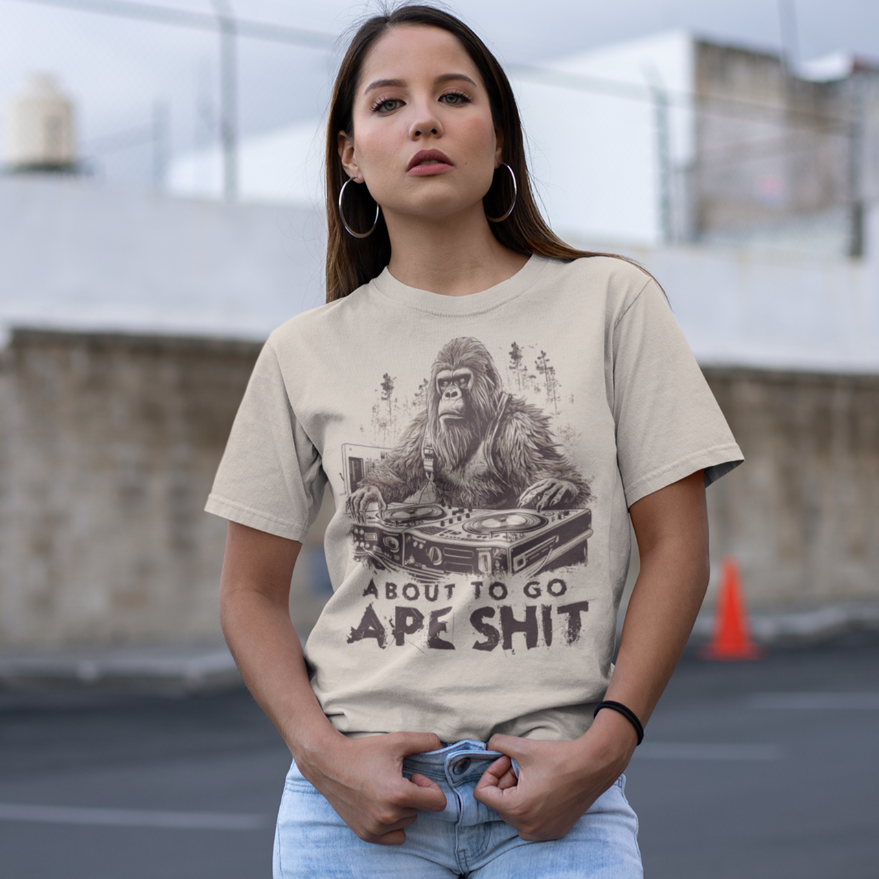 Cream t-shirt with a gorilla playing the decks in a forest with text underneath "ABOUT TO GO APE SHIT".