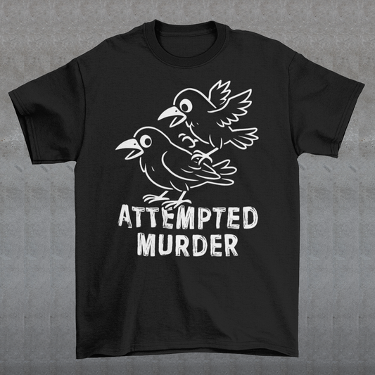 Serve up a little dark humor with a wink and a caw in this “Attempted Murder” t-shirt, a clever play on the classic term for a group of crows. Featuring two mischievous cartoon crows mid-chaos, this design turns a slightly sinister phrase into something irresistibly funny. It’s the kind of joke that lands somewhere between clever wordplay and delightfully inappropriate humor, perfect for those who enjoy their laughs with a shadowy twist.