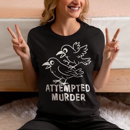 Serve up a little dark humor with a wink and a caw in this “Attempted Murder” t-shirt, a clever play on the classic term for a group of crows. Featuring two mischievous cartoon crows mid-chaos, this design turns a slightly sinister phrase into something irresistibly funny. It’s the kind of joke that lands somewhere between clever wordplay and delightfully inappropriate humor, perfect for those who enjoy their laughs with a shadowy twist.