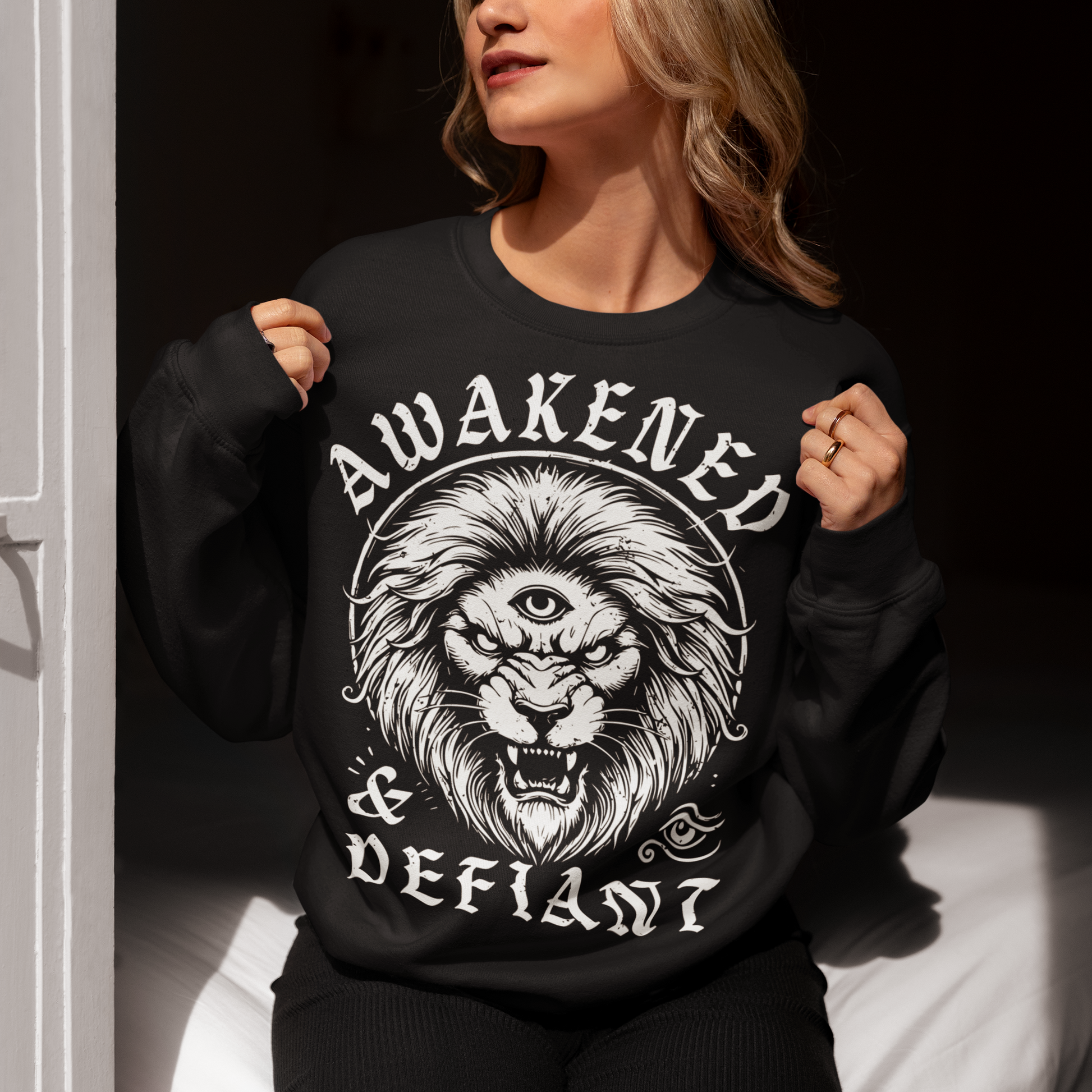 Unleash your inner power with this bold and striking sweatshirt featuring a fierce lion with a mystical third eye, symbolizing heightened awareness and untamed strength. The detailed artwork showcases the lion’s intense gaze, radiating wisdom and defiance, while the text "AWAKENED and DEFIANT" amplifies the message of resilience and enlightenment. This sweatshirt is perfect for those who stand fearless, awakened, and unapologetically themselves. Wear it and embrace the spirit of the untamed.
