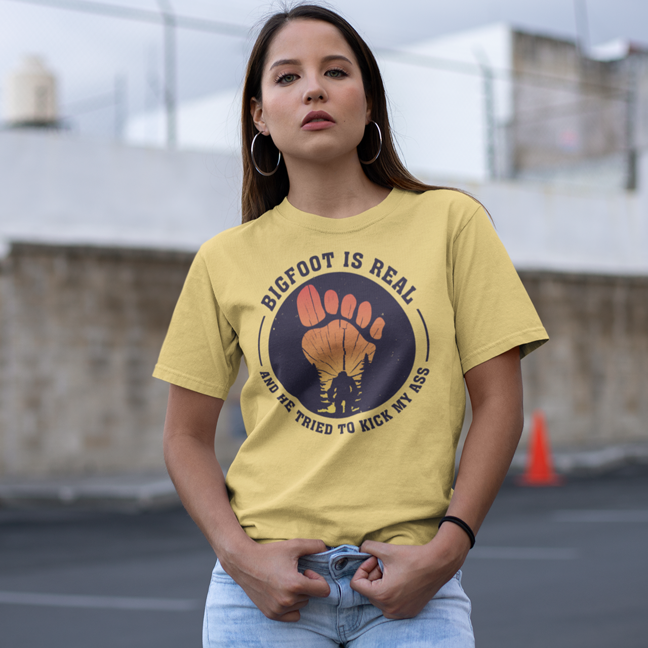 Yellow t-shirt with a bigfoot silhouette on a sunset foot with text "BIGFOOT IS REAL AND HE TRIED TO KICK MY ASS".