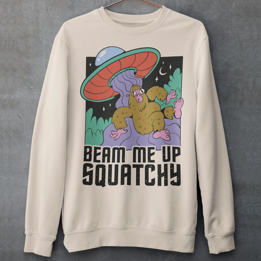 Cream sweatshirt of a sasquatch being abducted by a UFO with text BEAM ME UP SQUATCHY.