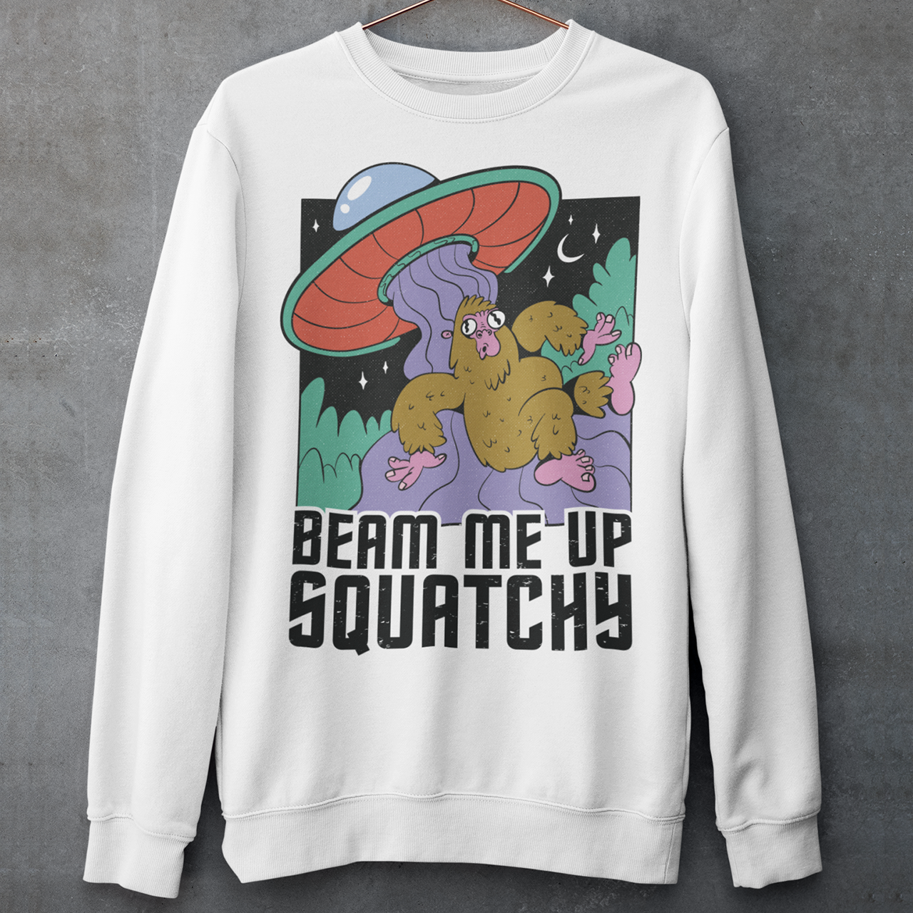 White sweatshirt of a sasquatch being abducted by a UFO with text BEAM ME UP SQUATCHY.