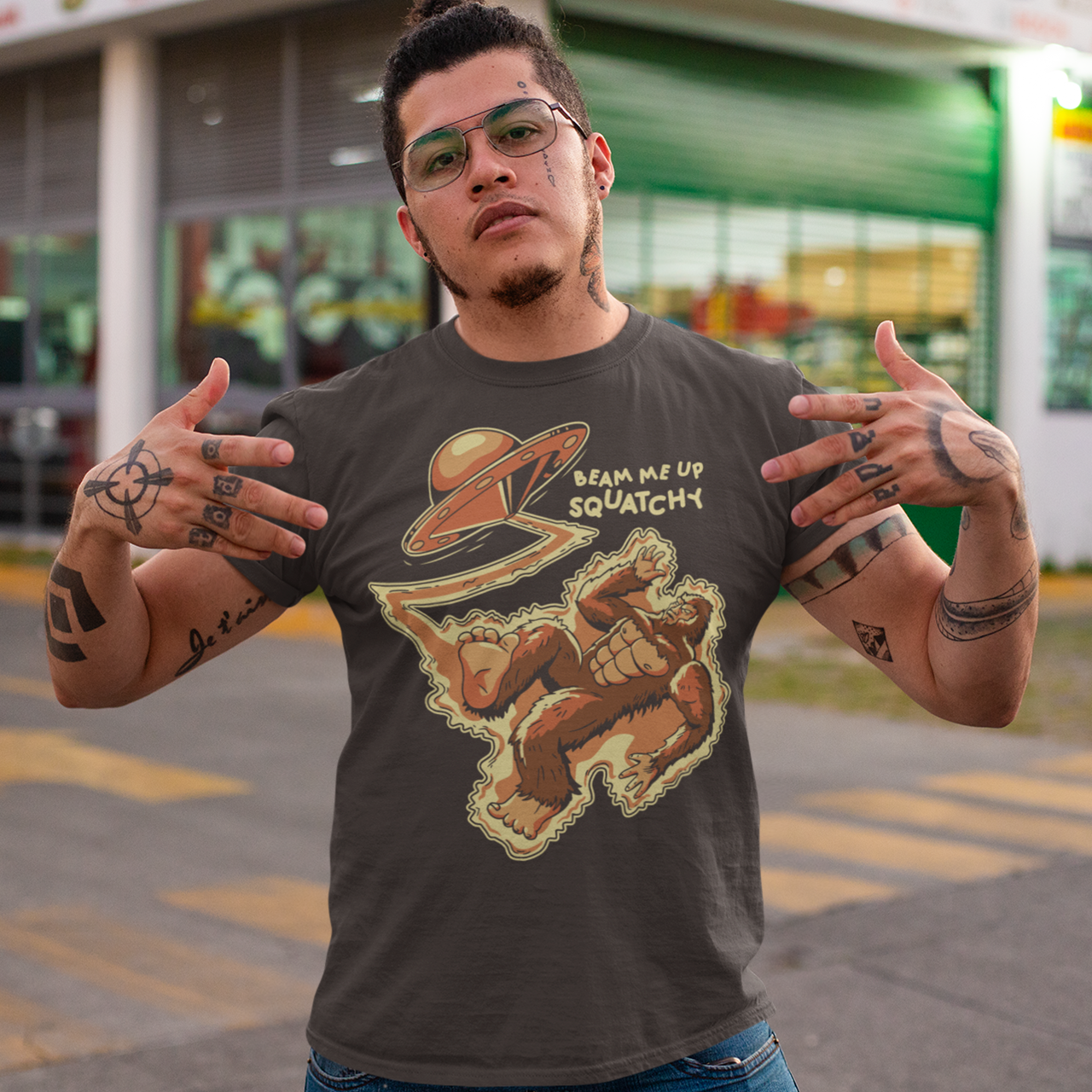 Brown t-shirt featuring a Sasquatch being abducted by a UFO with text "BEAM ME UP SQUATCHY".