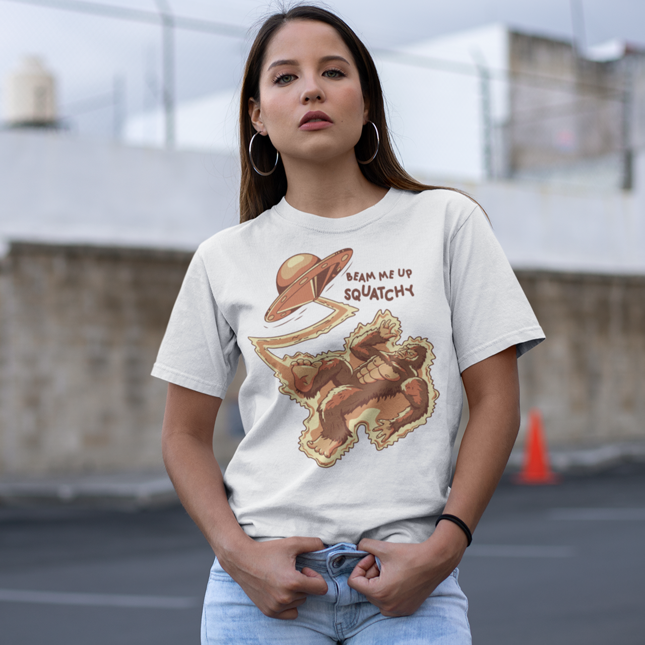 White t-shirt featuring a Sasquatch being abducted by a UFO  with text  "BEAM ME UP SQUATCHY".